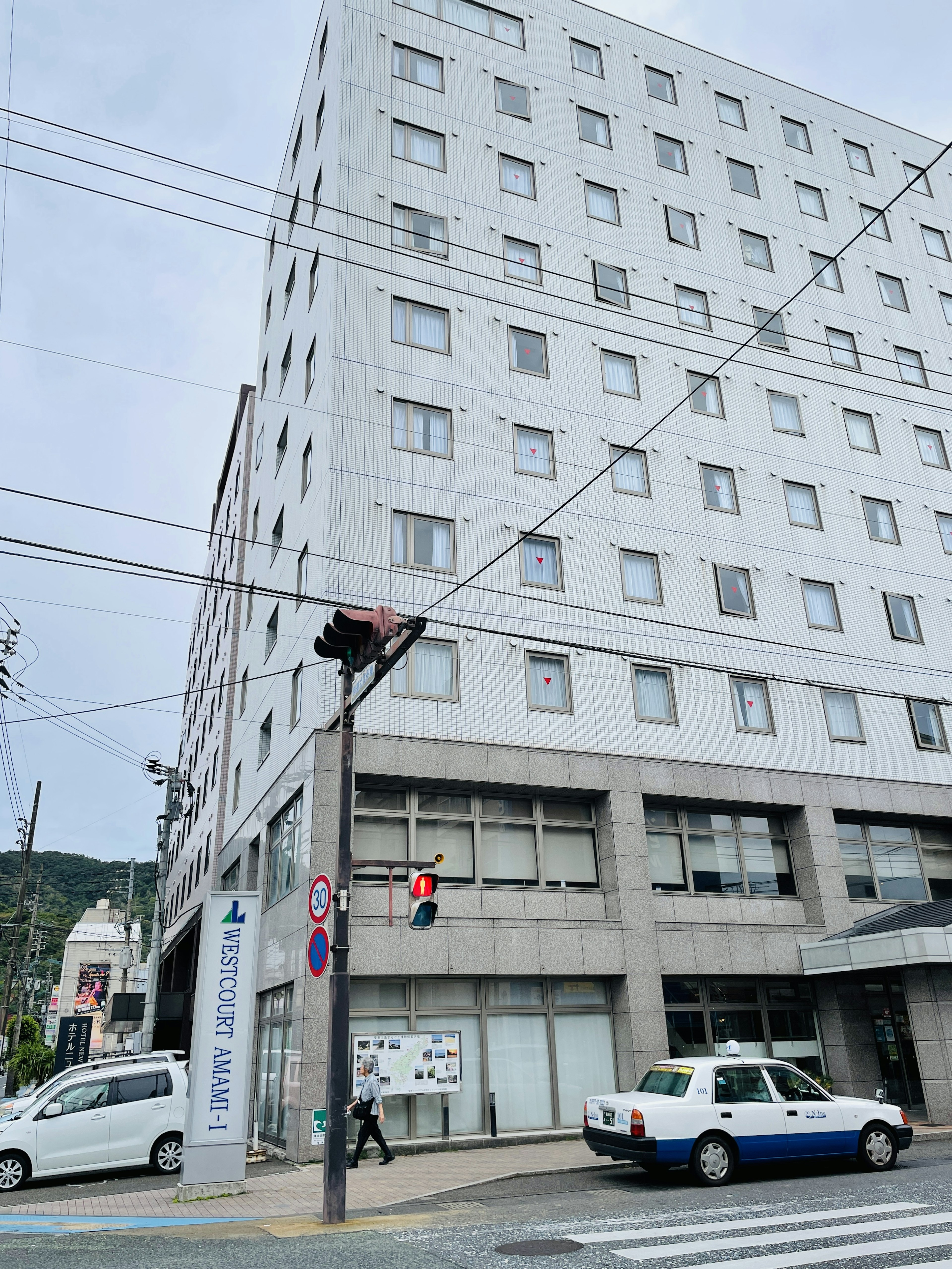 Vista de la calle con un edificio blanco y un semáforo peatonal