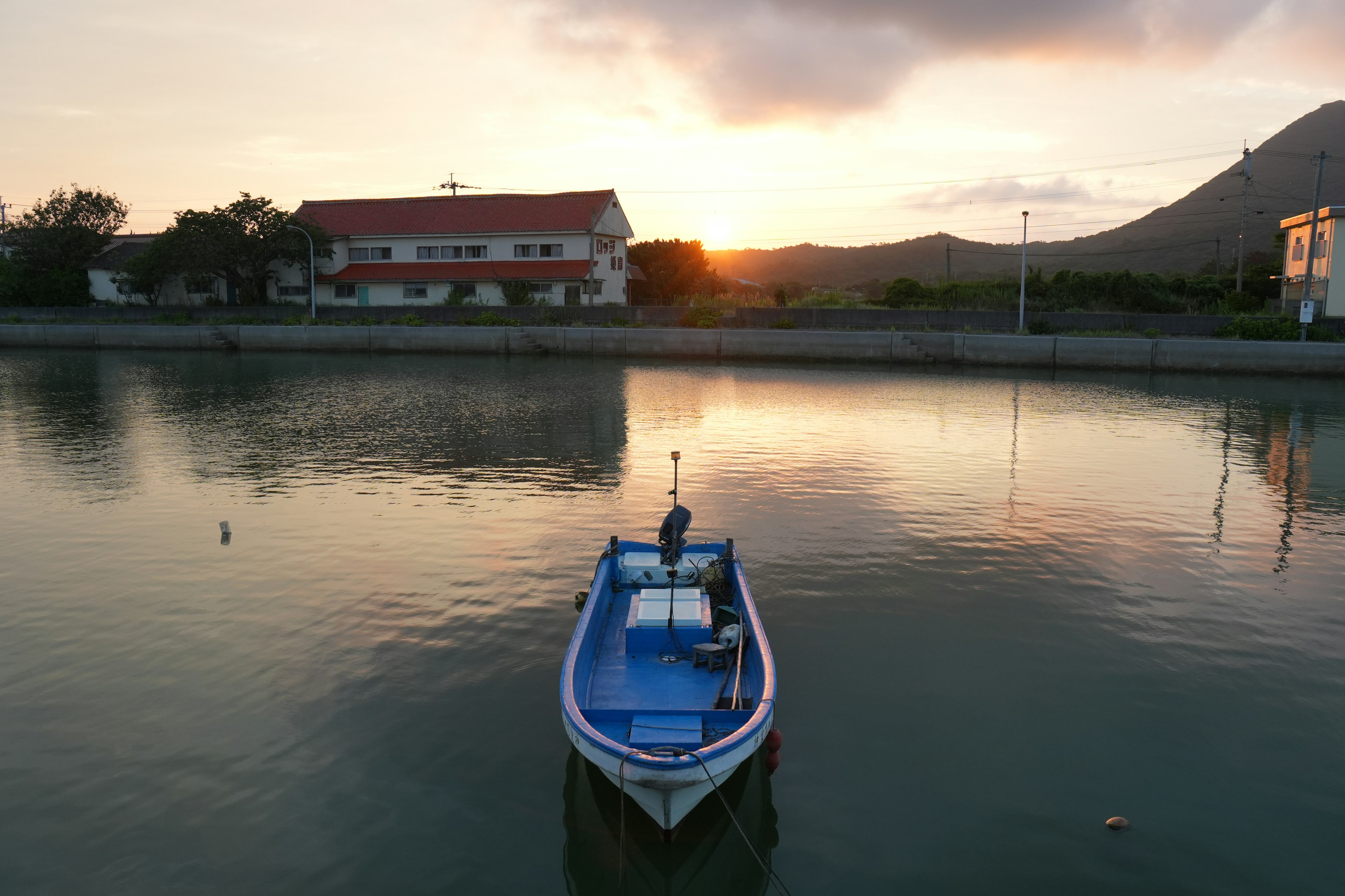 Un bateau bleu flottant sur un lac calme avec un magnifique coucher de soleil