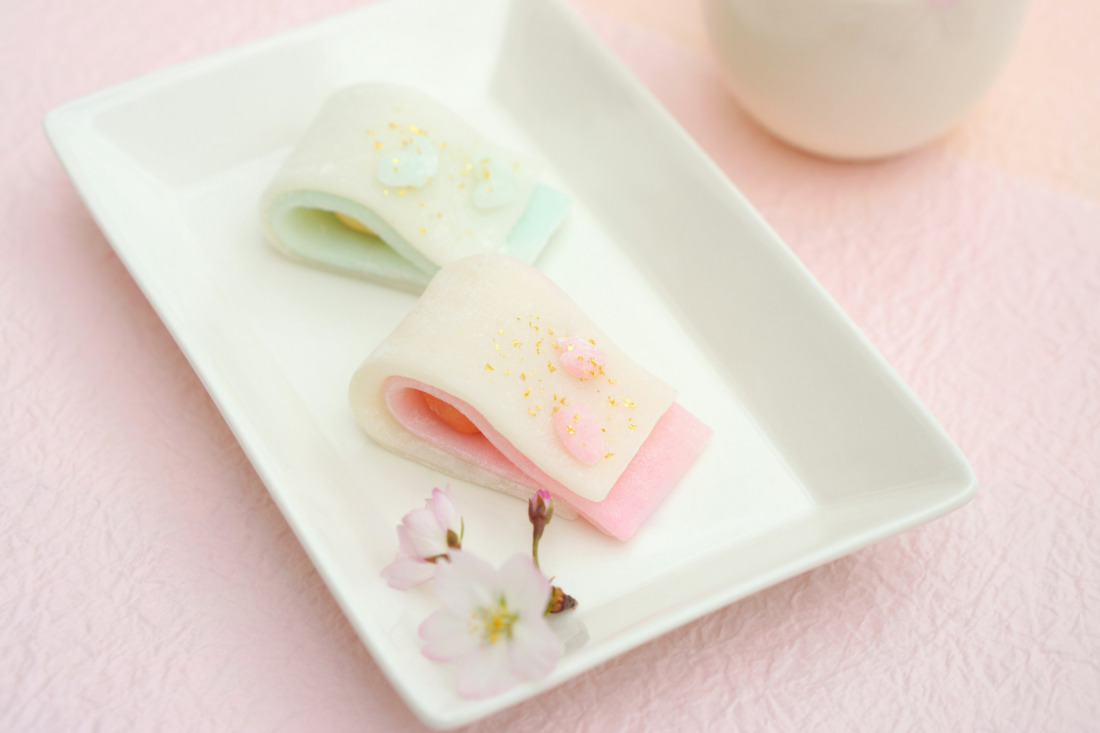 Dulces japoneses coloridos en un plato blanco con flores de cerezo