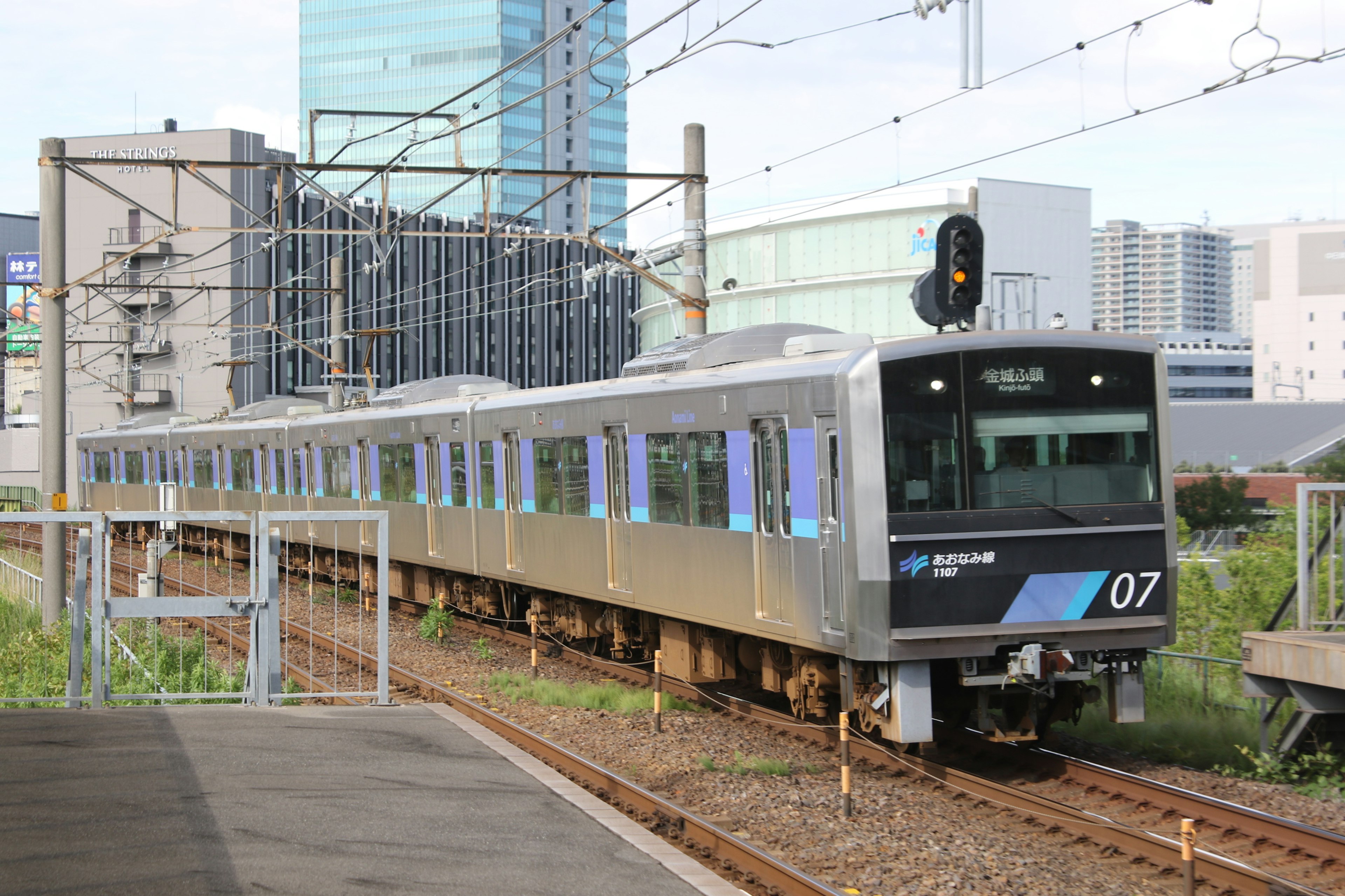 Urban train traveling on tracks with modern buildings in background