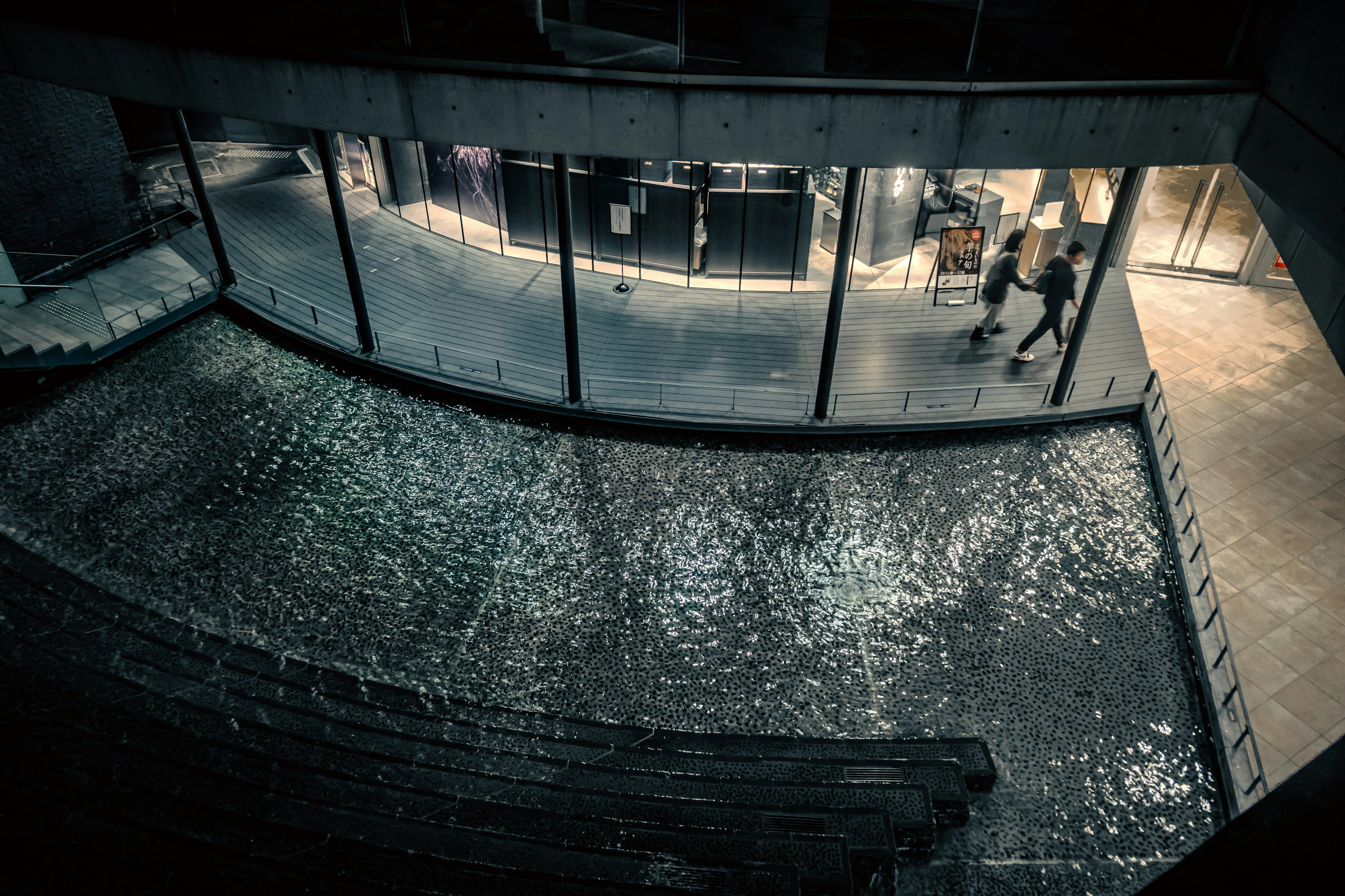 A commercial space with flowing water and glass walls in a dark setting