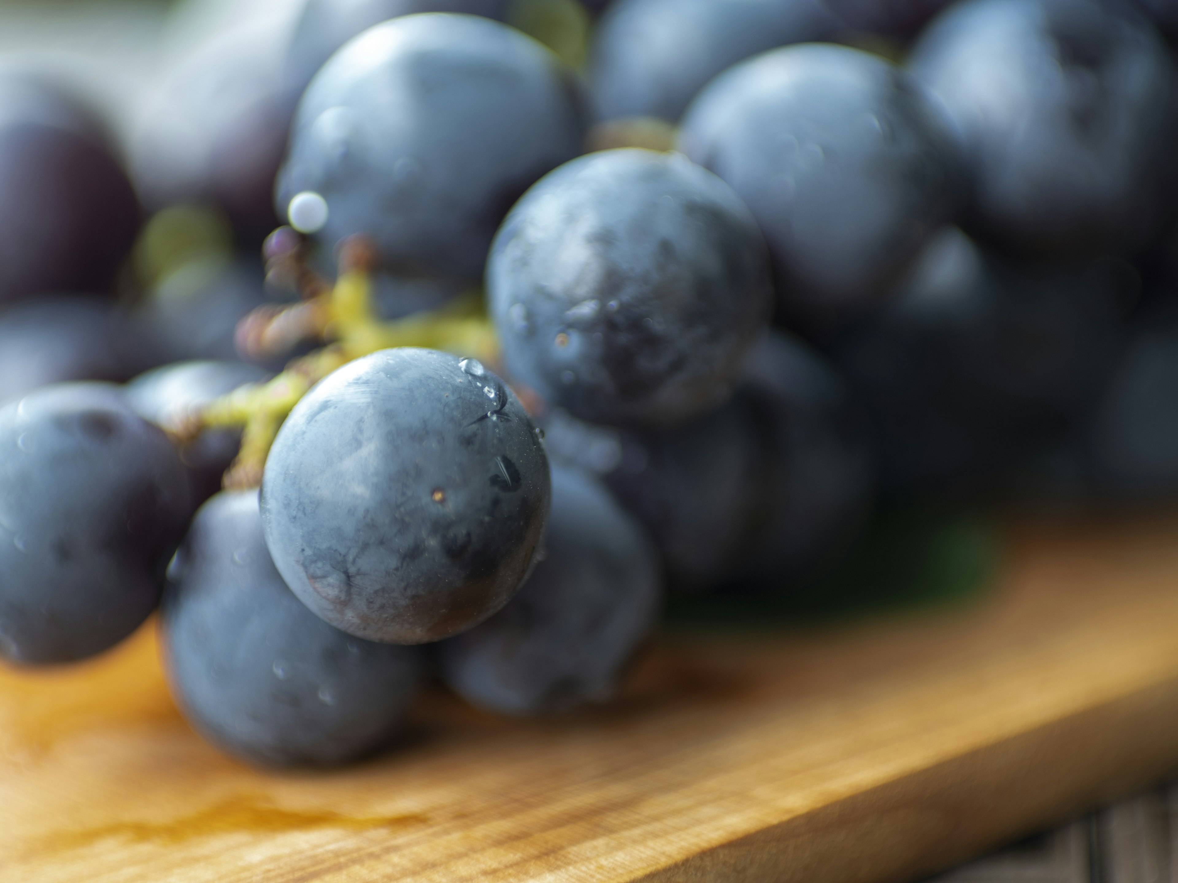 Grappolo di uva blu-viola fresca su un tagliere di legno