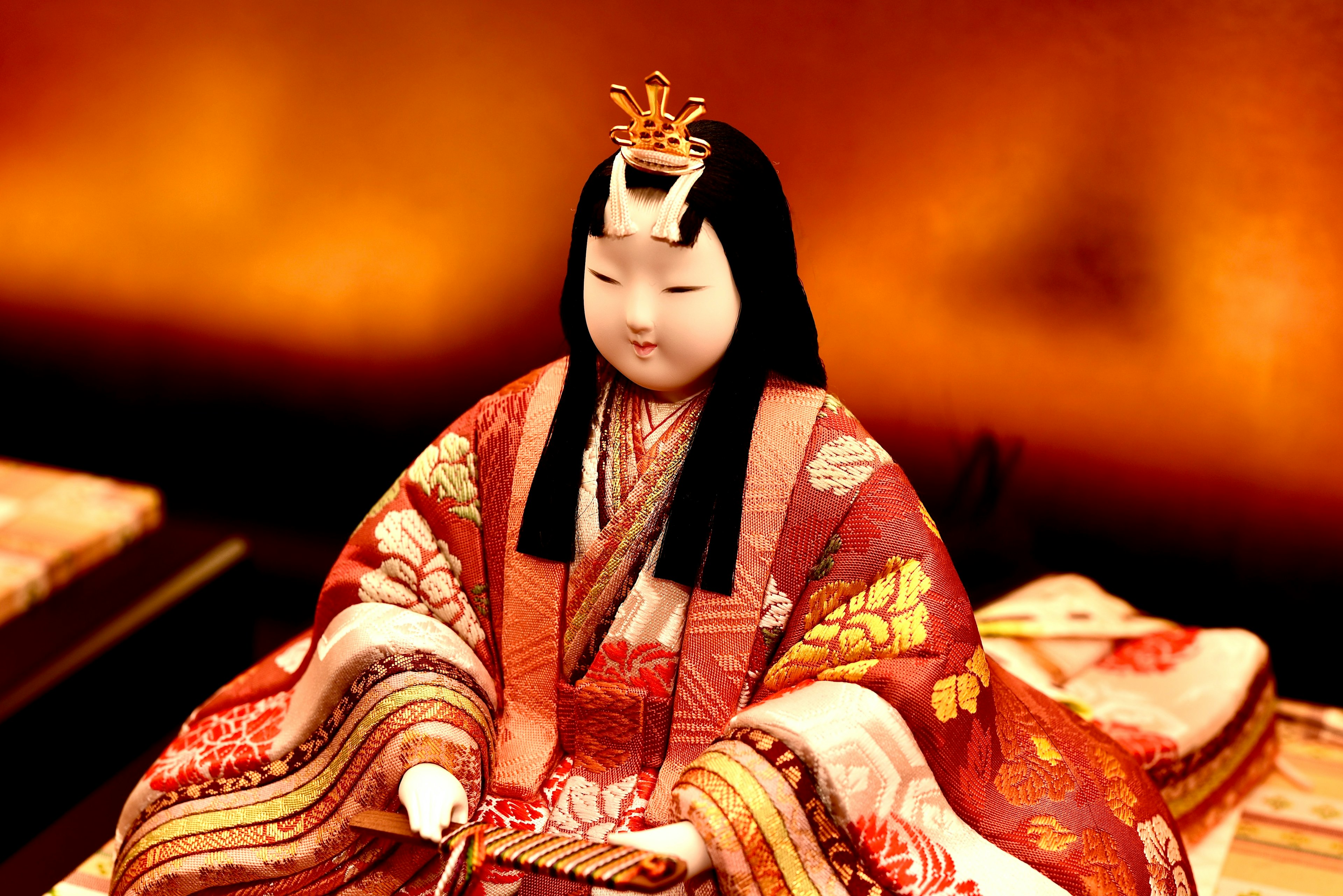 A beautiful traditional hina doll seated against a golden background