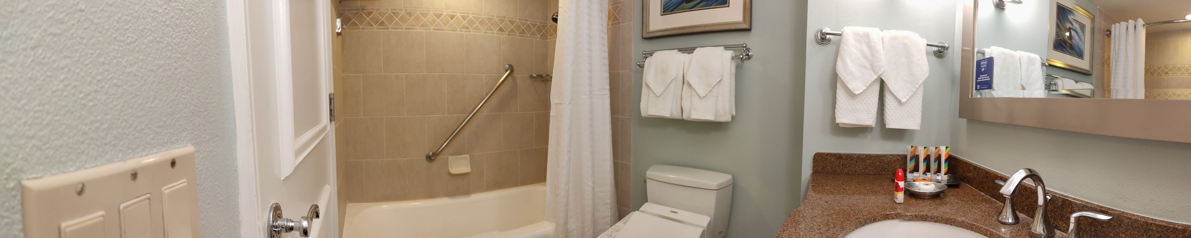 Clean and modern bathroom interior featuring a toilet and sink colorful towels and a mirror