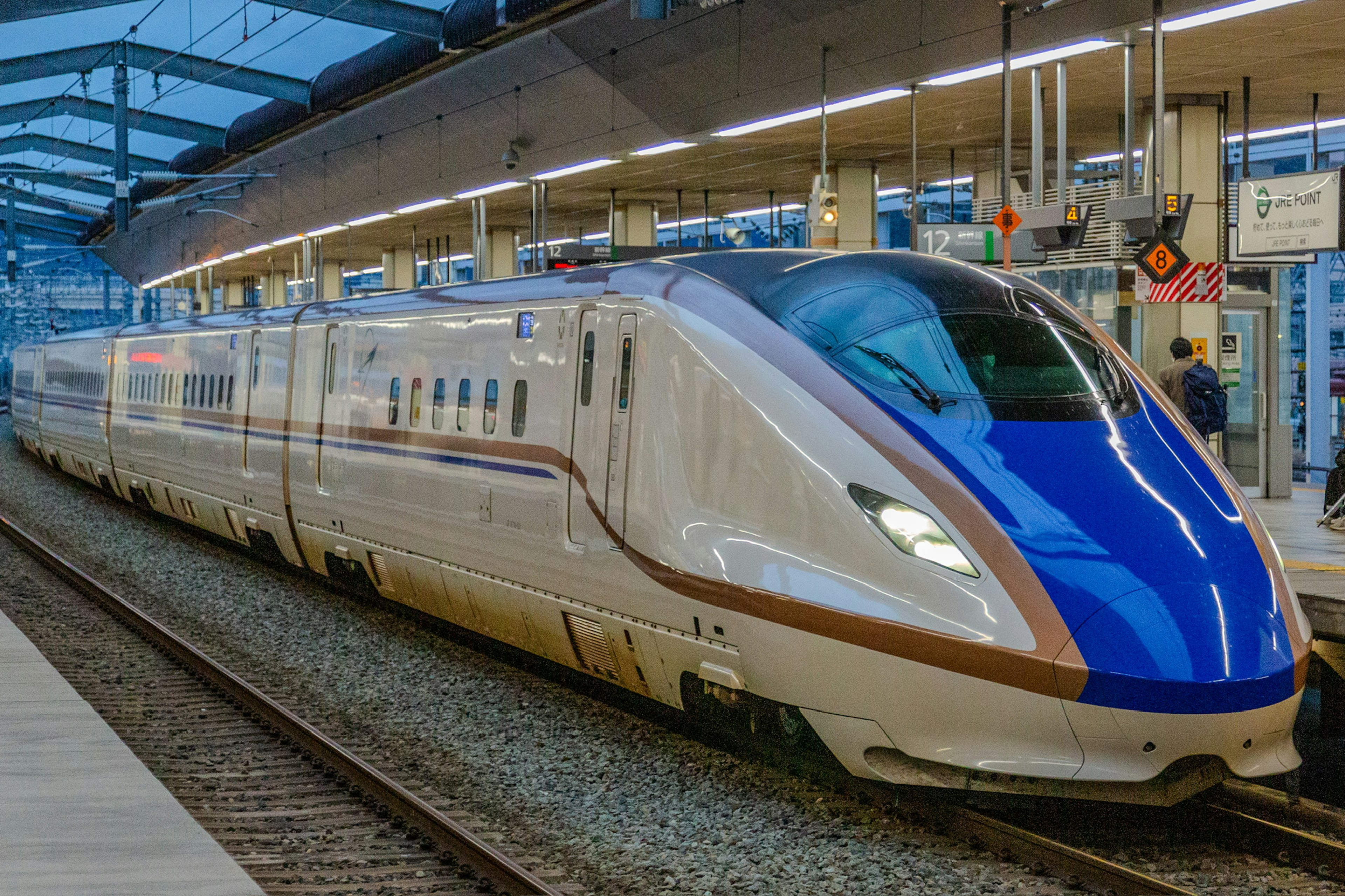 Kereta Shinkansen dengan desain ramping dan atap biru terparkir di stasiun