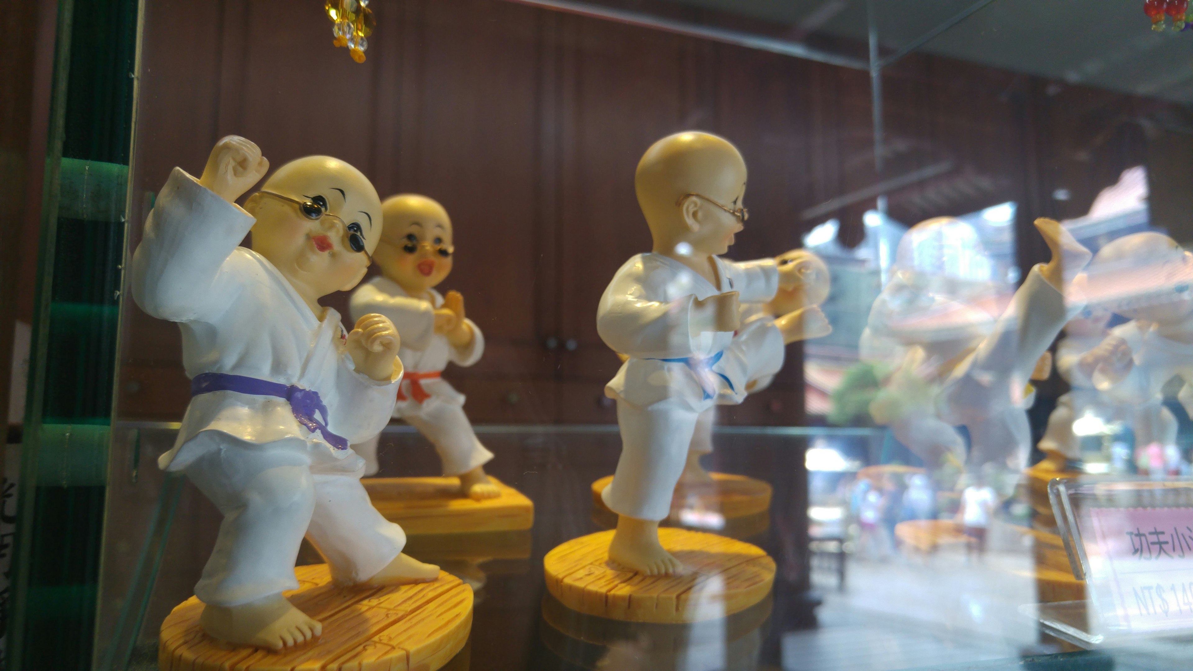 Figurines de karaté colorées exposées dans une vitrine en verre