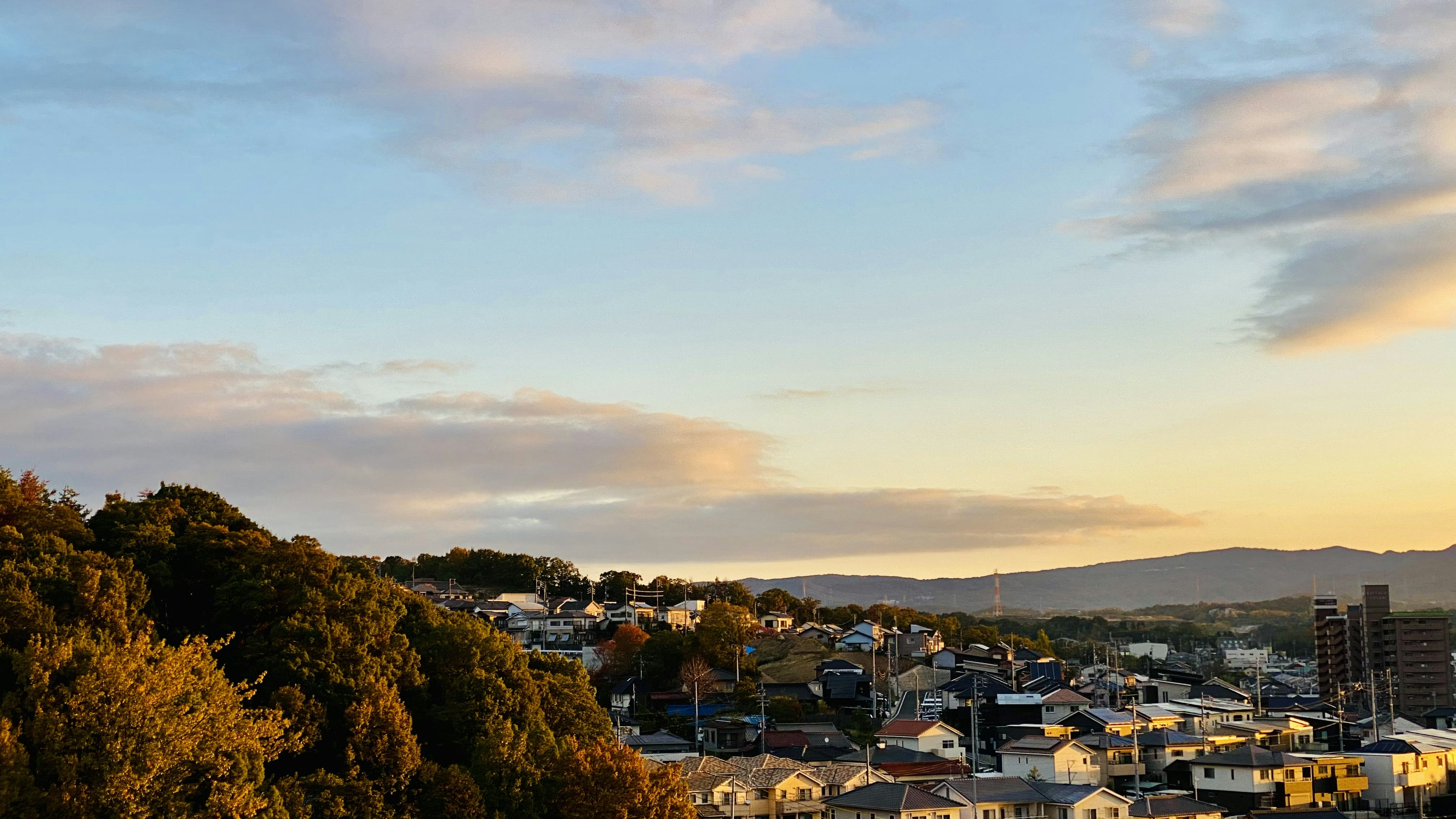 Twilight view of a town with hills and clouds