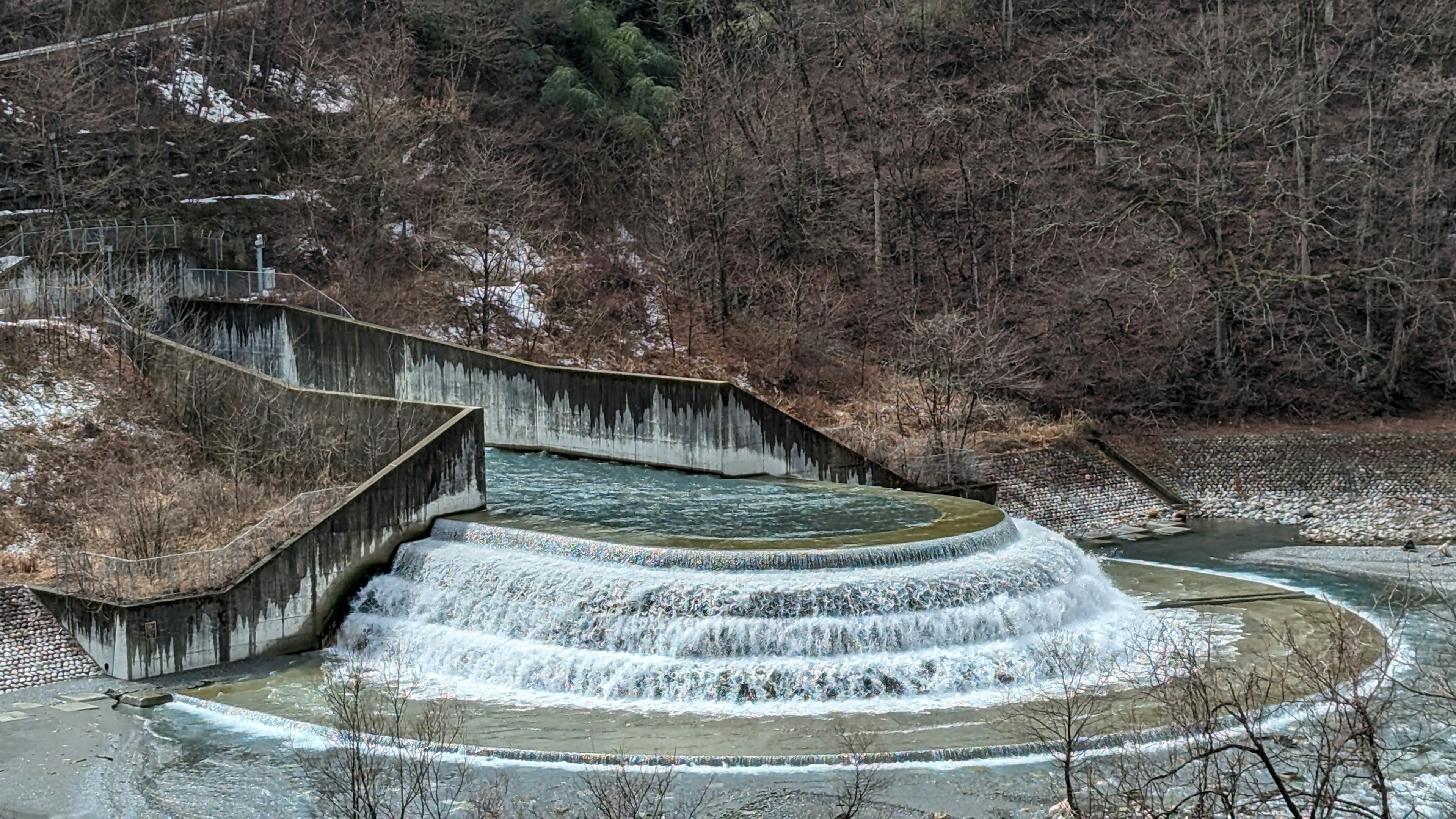 Une cascade avec une structure courbée et des arbres environnants