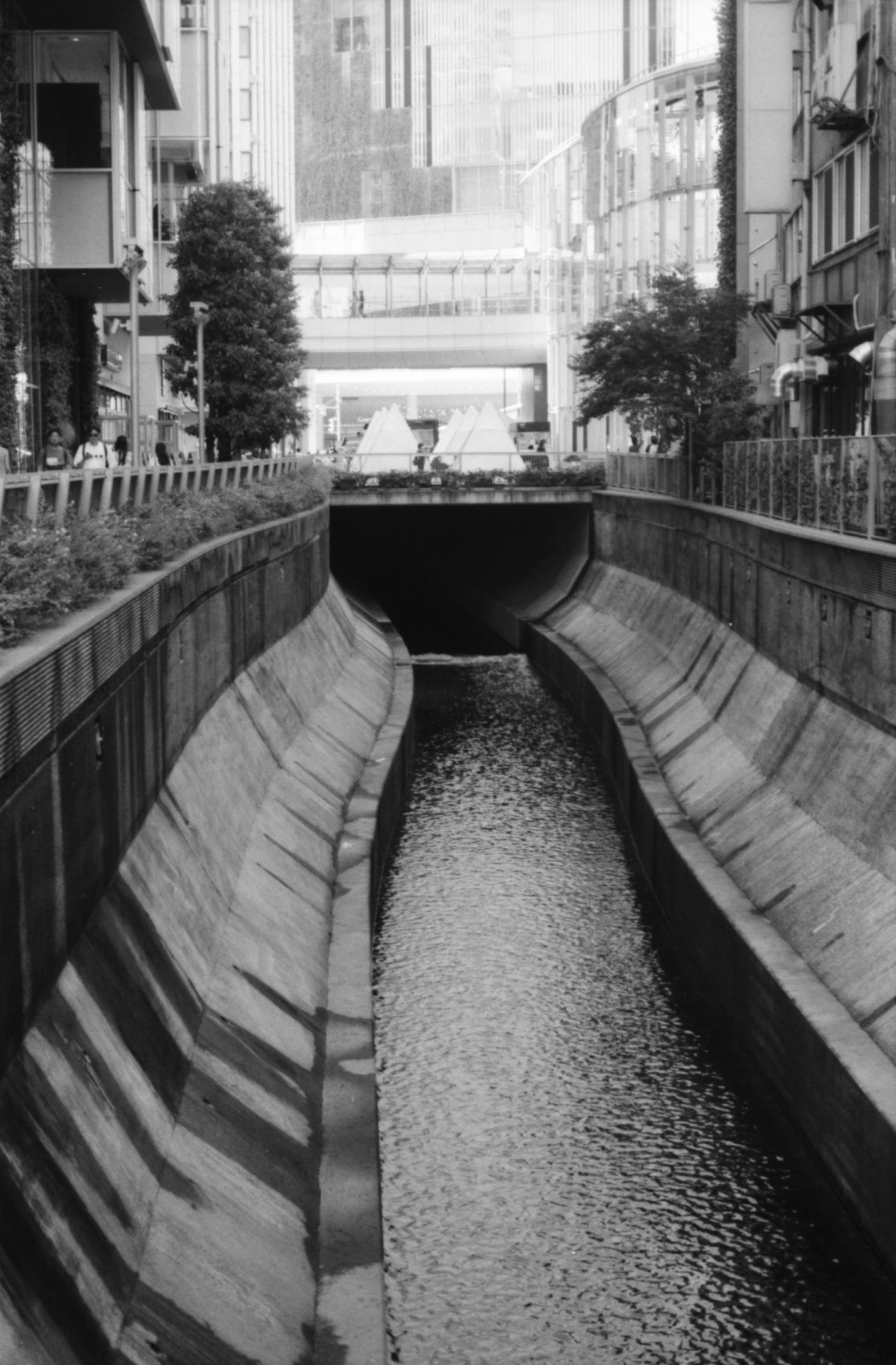 Imagen en blanco y negro de un canal urbano con altas paredes a ambos lados