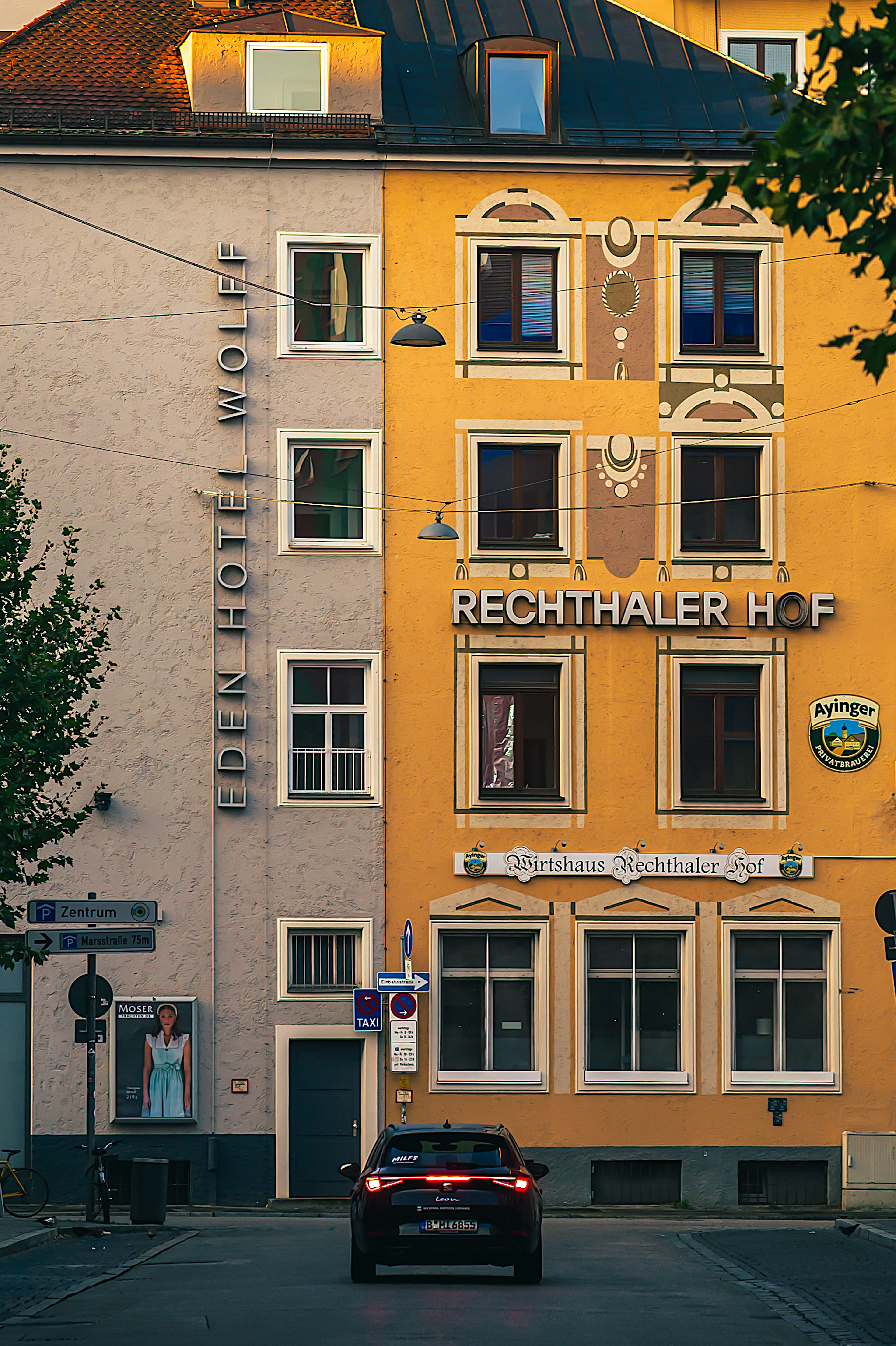 Vista exterior del Rechthaler Hof con fachada naranja y hotel adyacente