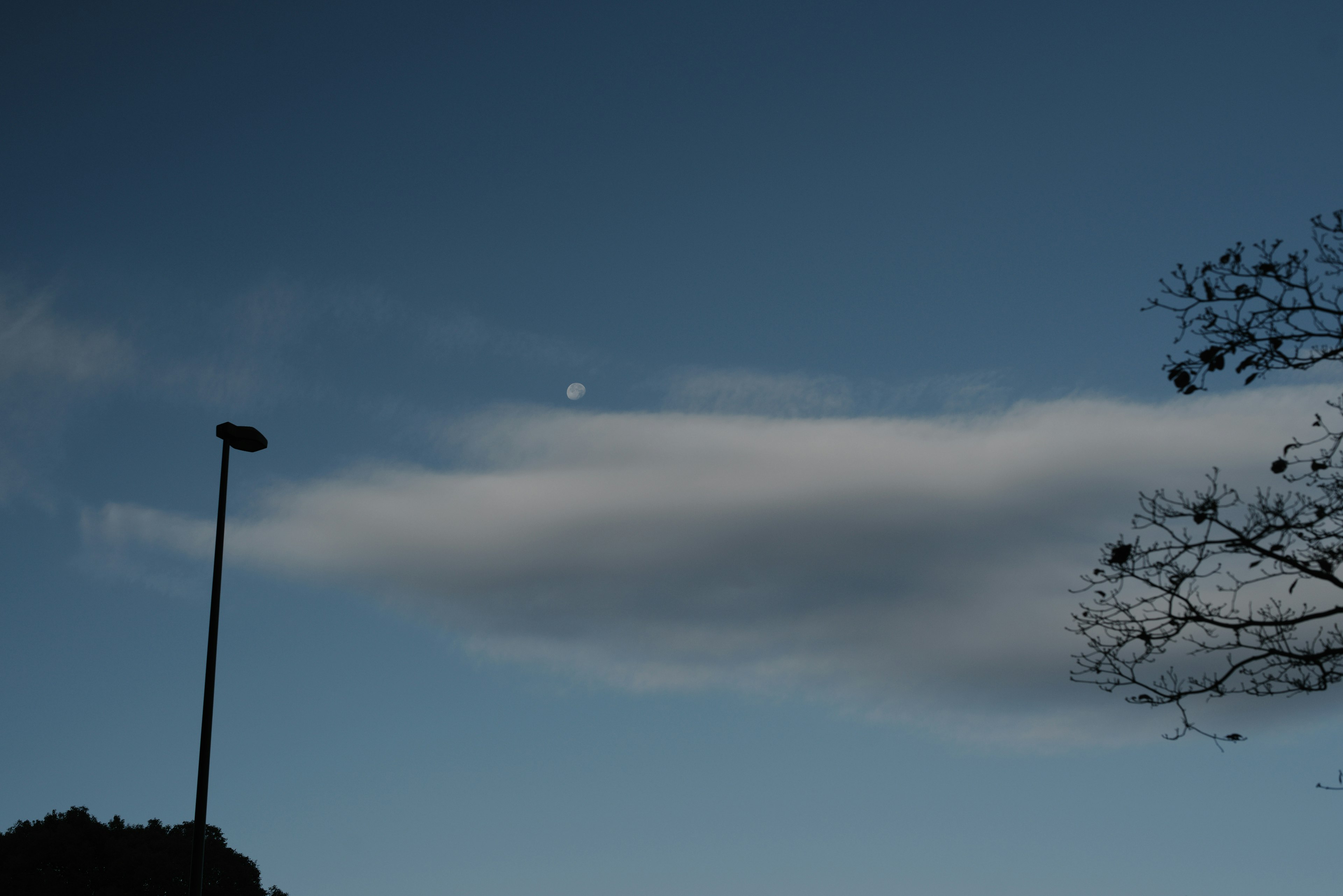 Wolken treiben in einem blauen Himmel mit einem Hauch von Mondlicht