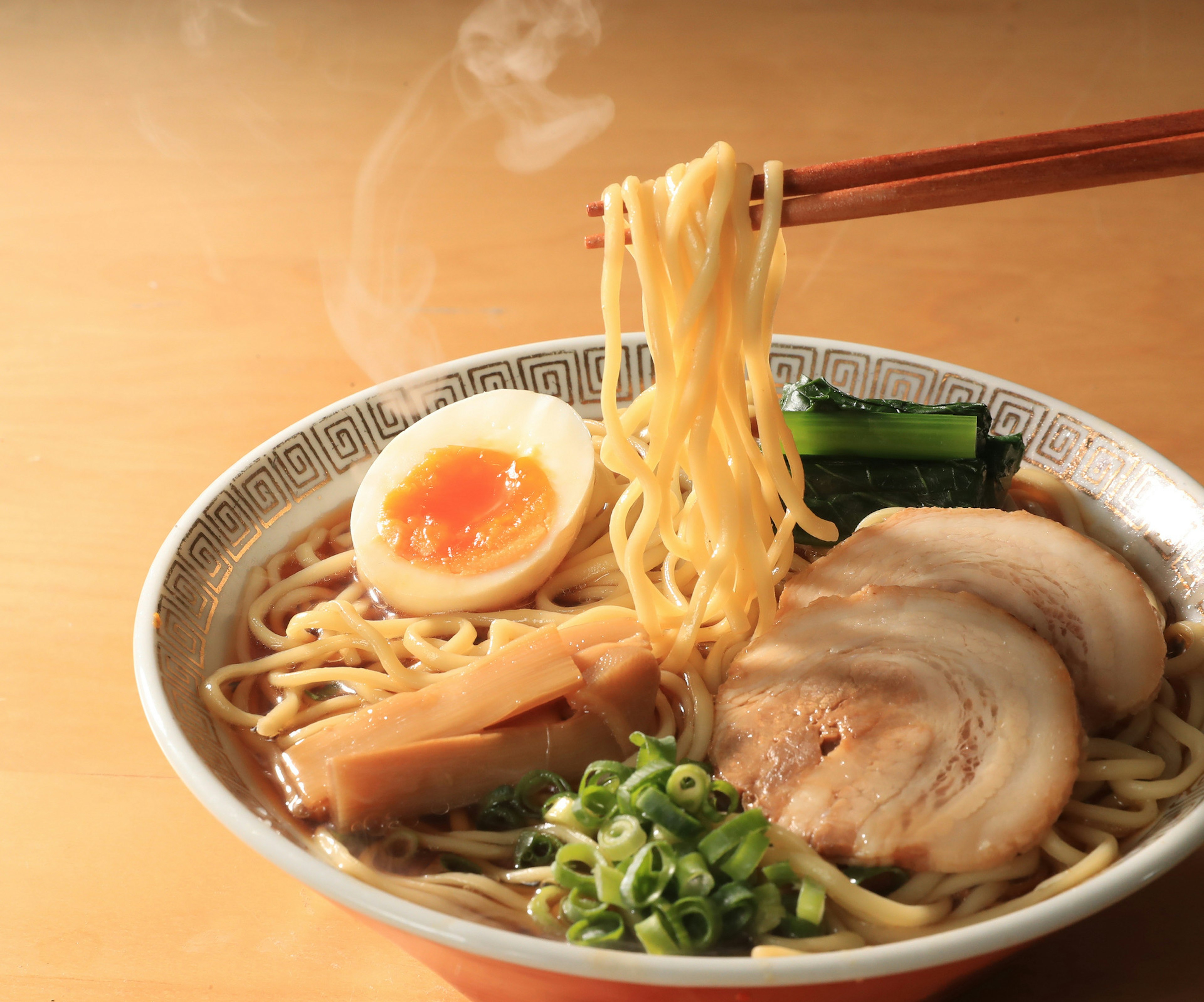 Bowl di ramen fumante con maiale affettato, uovo sodo e cipollotti