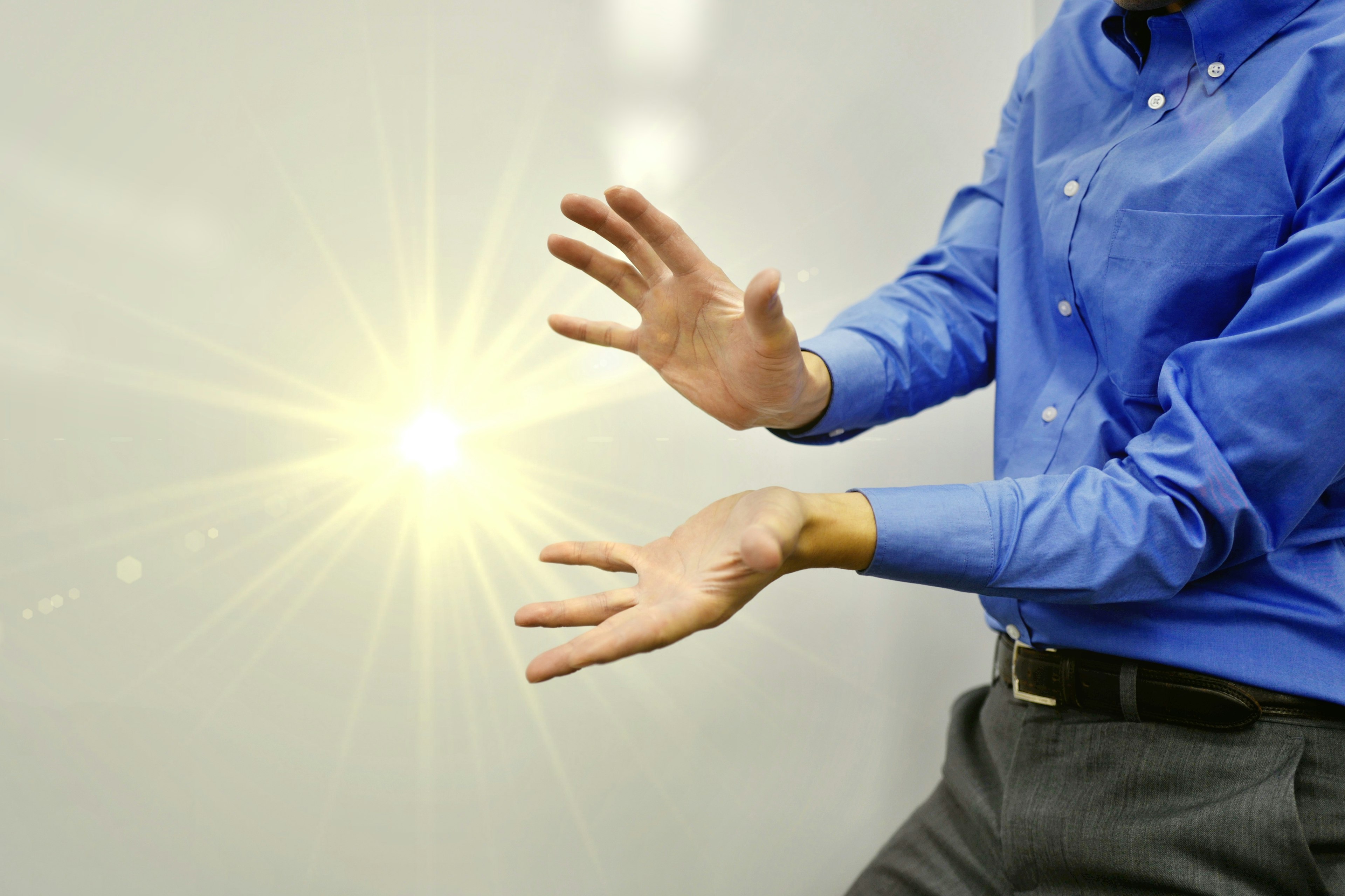 Un uomo in camicia blu sembra tenere luce tra le mani