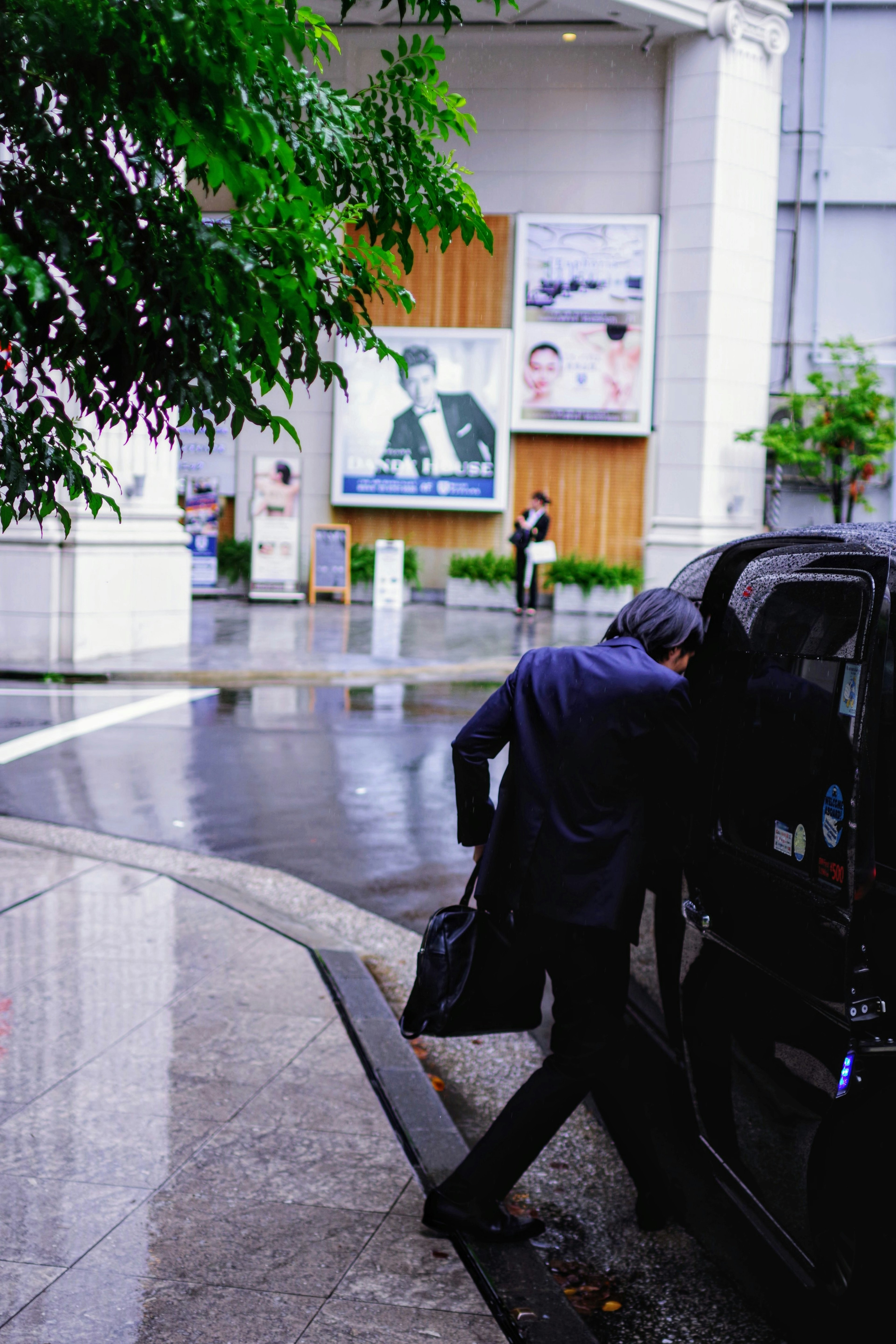 穿着西装的男人在雨中上车，背景有广告