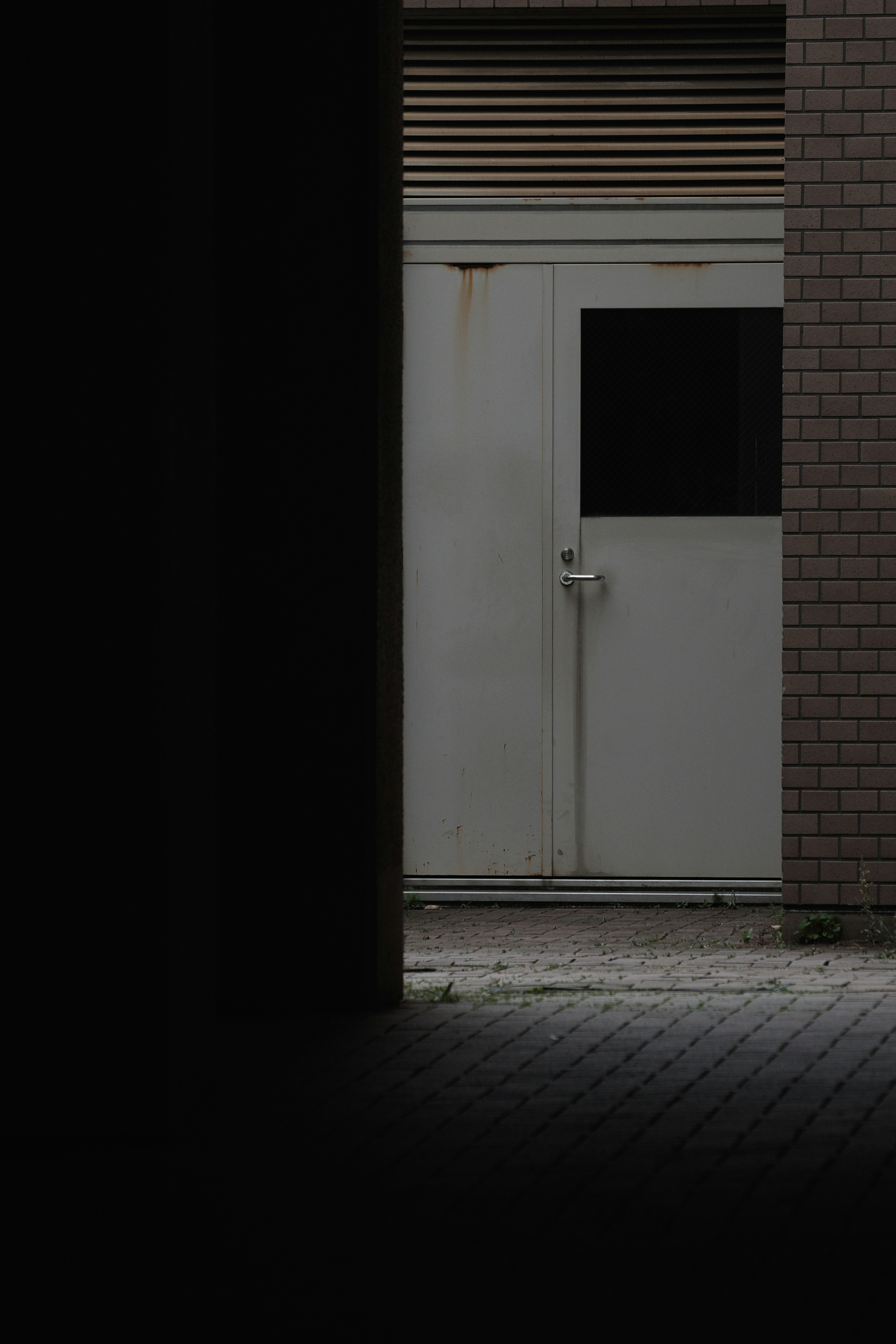 Une porte blanche au bout d'un couloir sombre avec des murs environnants