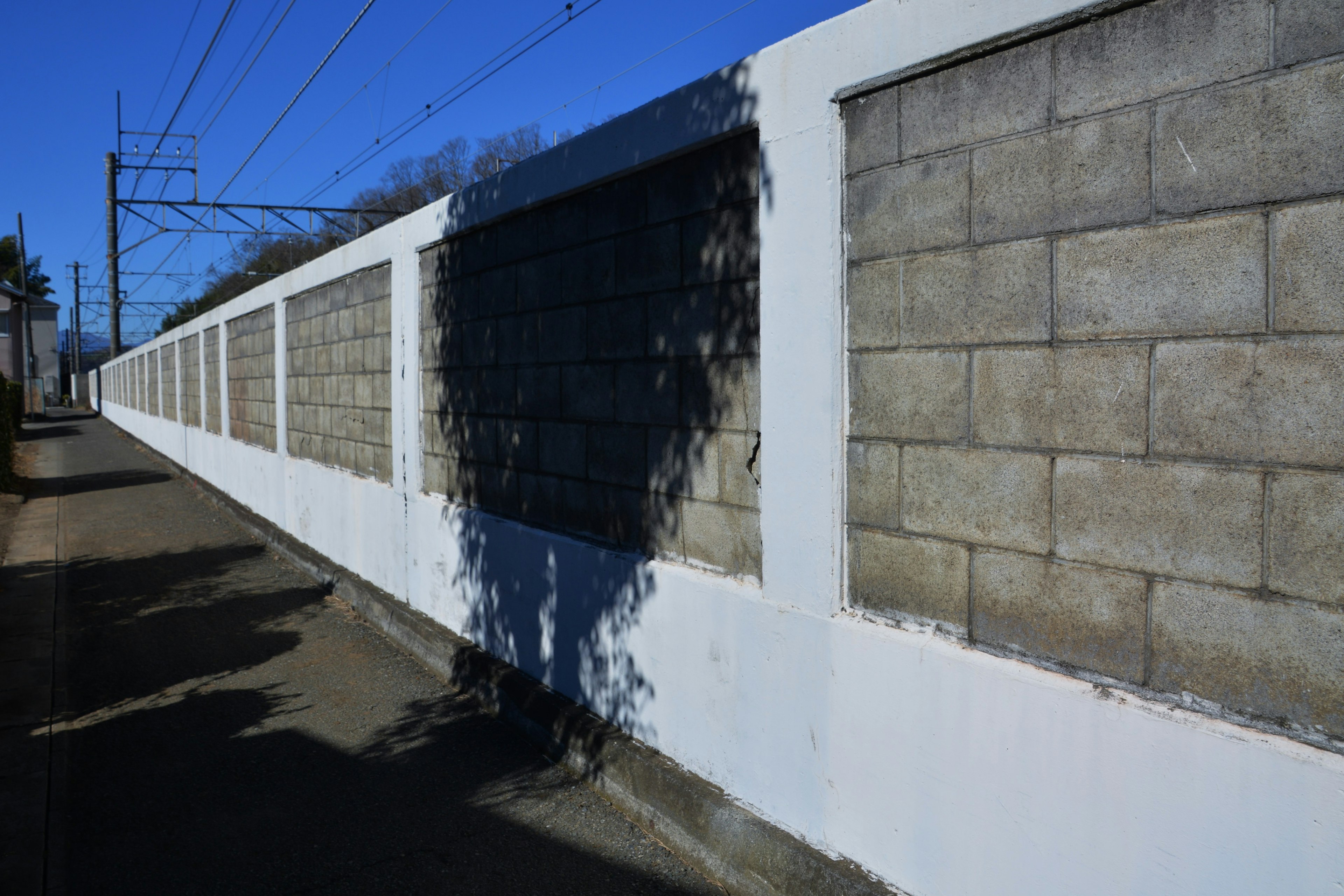 Concrete wall with white paint and shadow cast on the ground