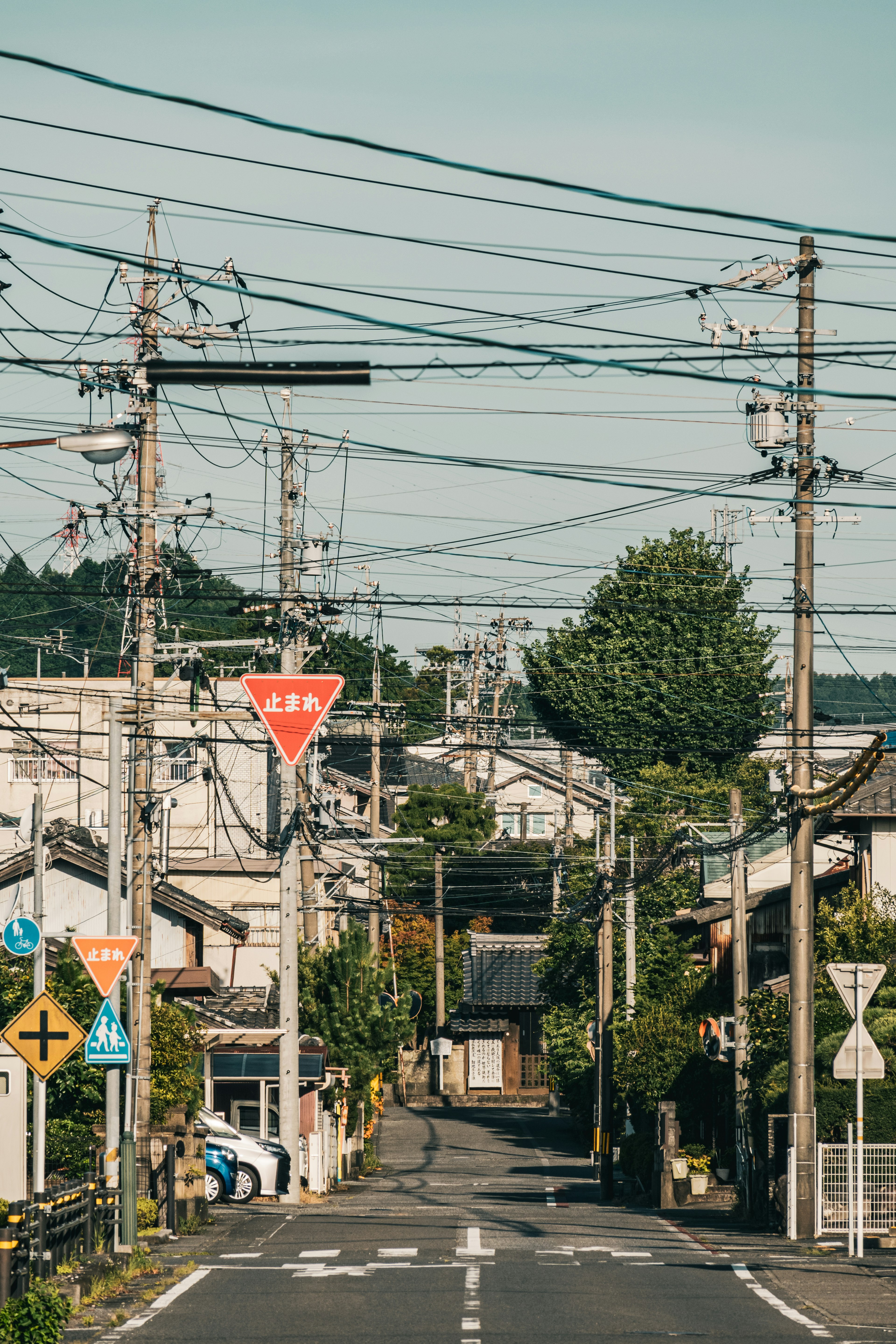 Quiet residential street in Japan with intersecting power lines and traffic signs