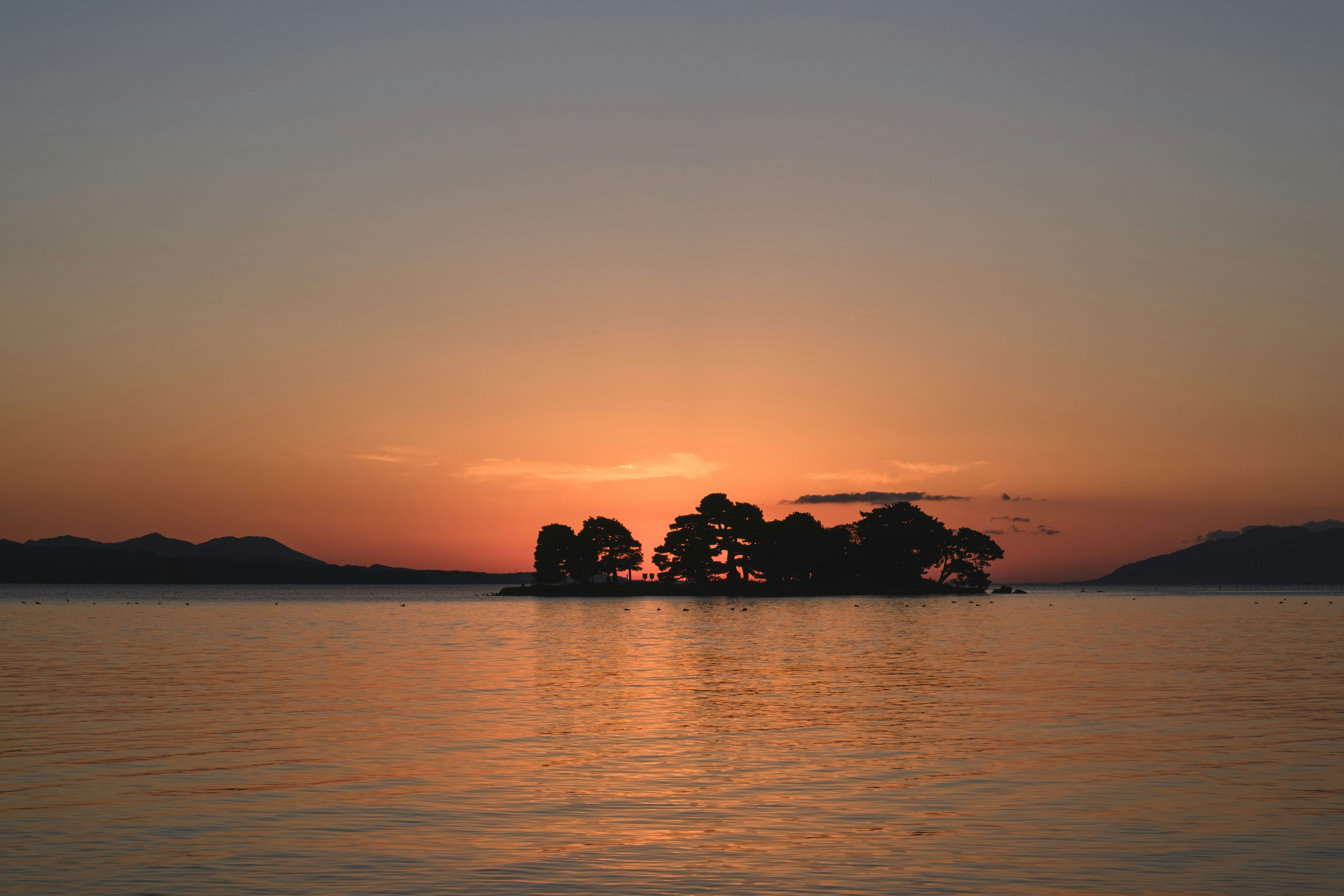 夕日の中に浮かぶ島と静かな水面