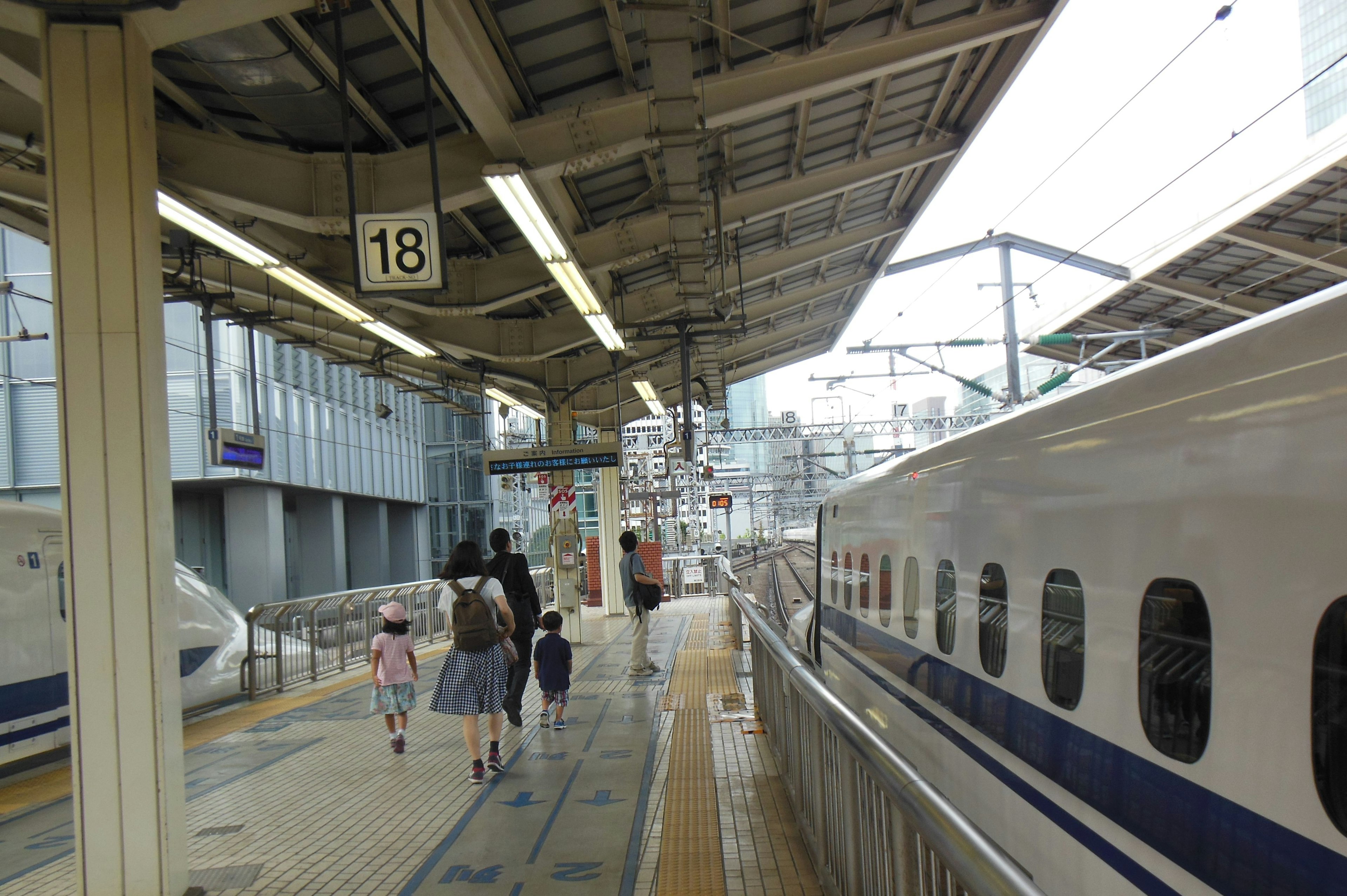 Familie, die auf Gleis 18 an einer Shinkansen-Station mit einem geparkten Zug geht