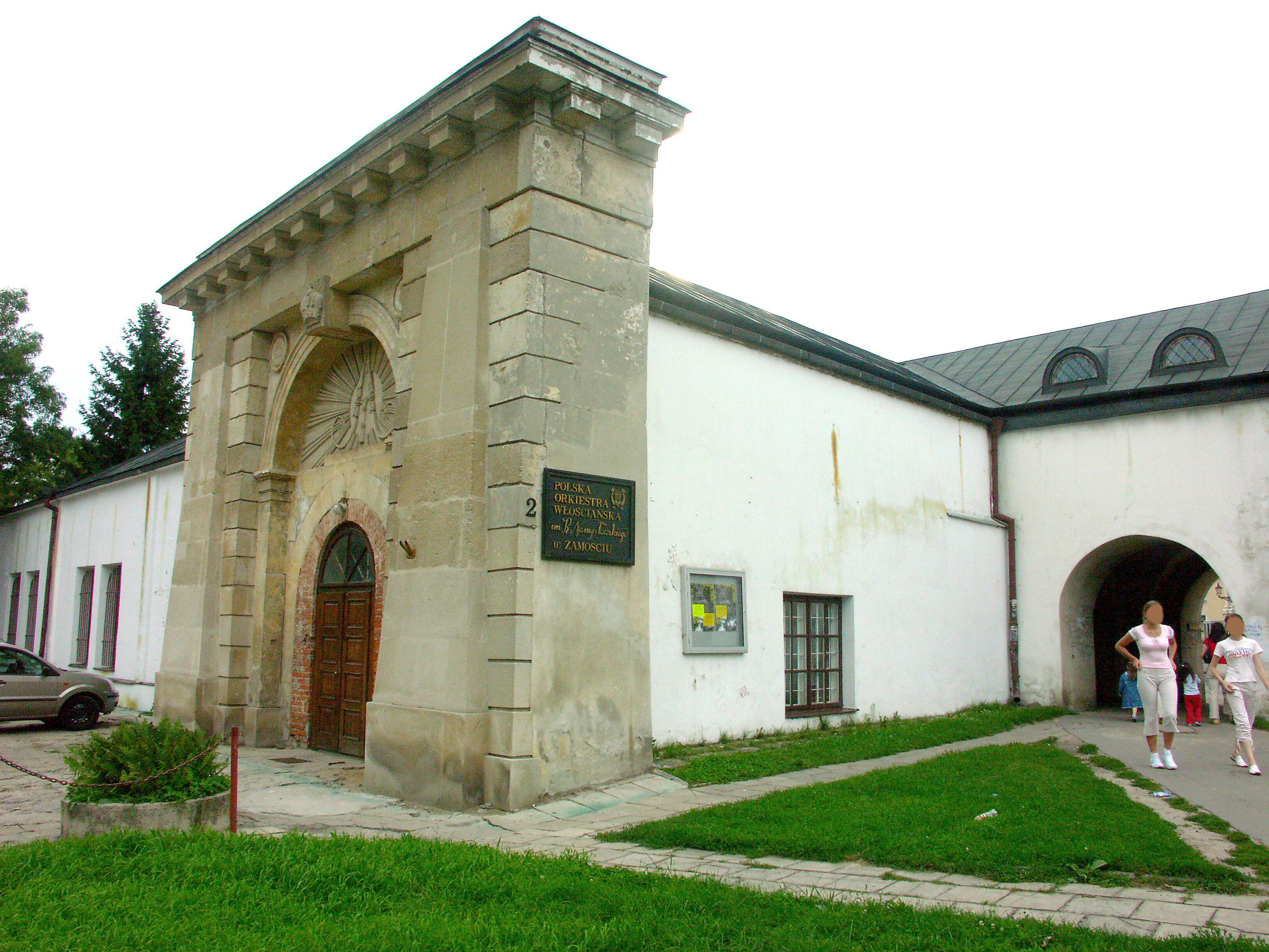 Exterior de un edificio histórico con una entrada en arco y paredes blancas