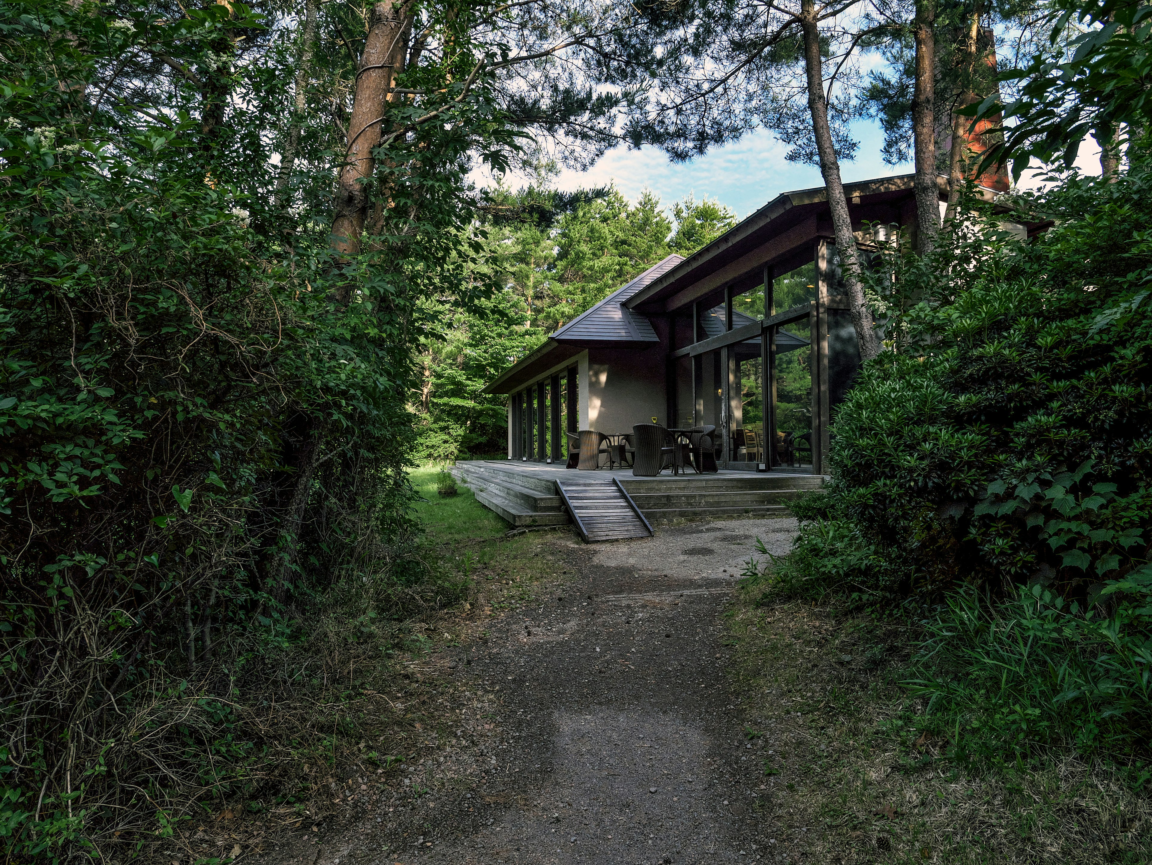 Extérieur d'une maison moderne entourée de verdure avec une terrasse en bois