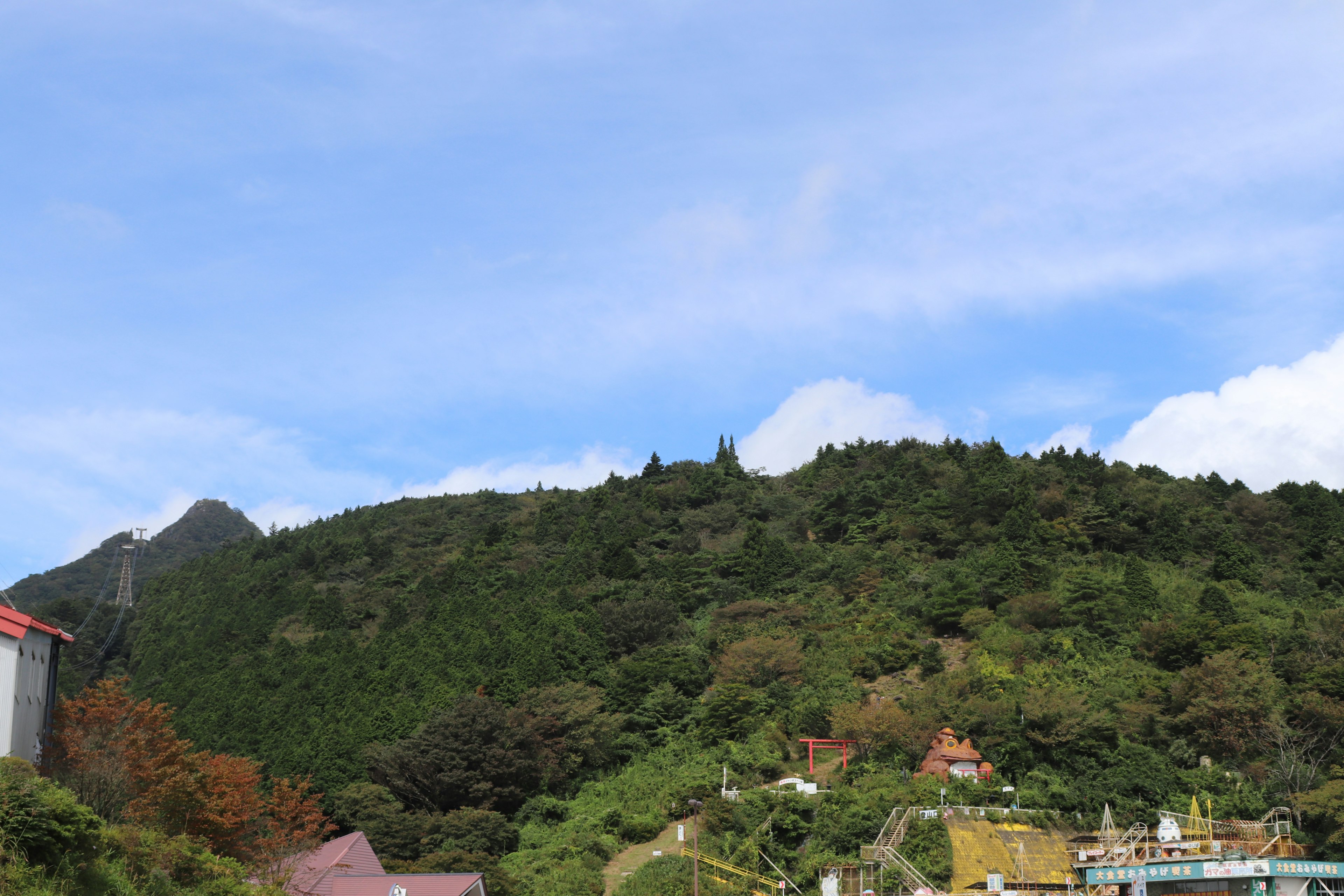 Montagna verde sotto un cielo blu con edifici circostanti