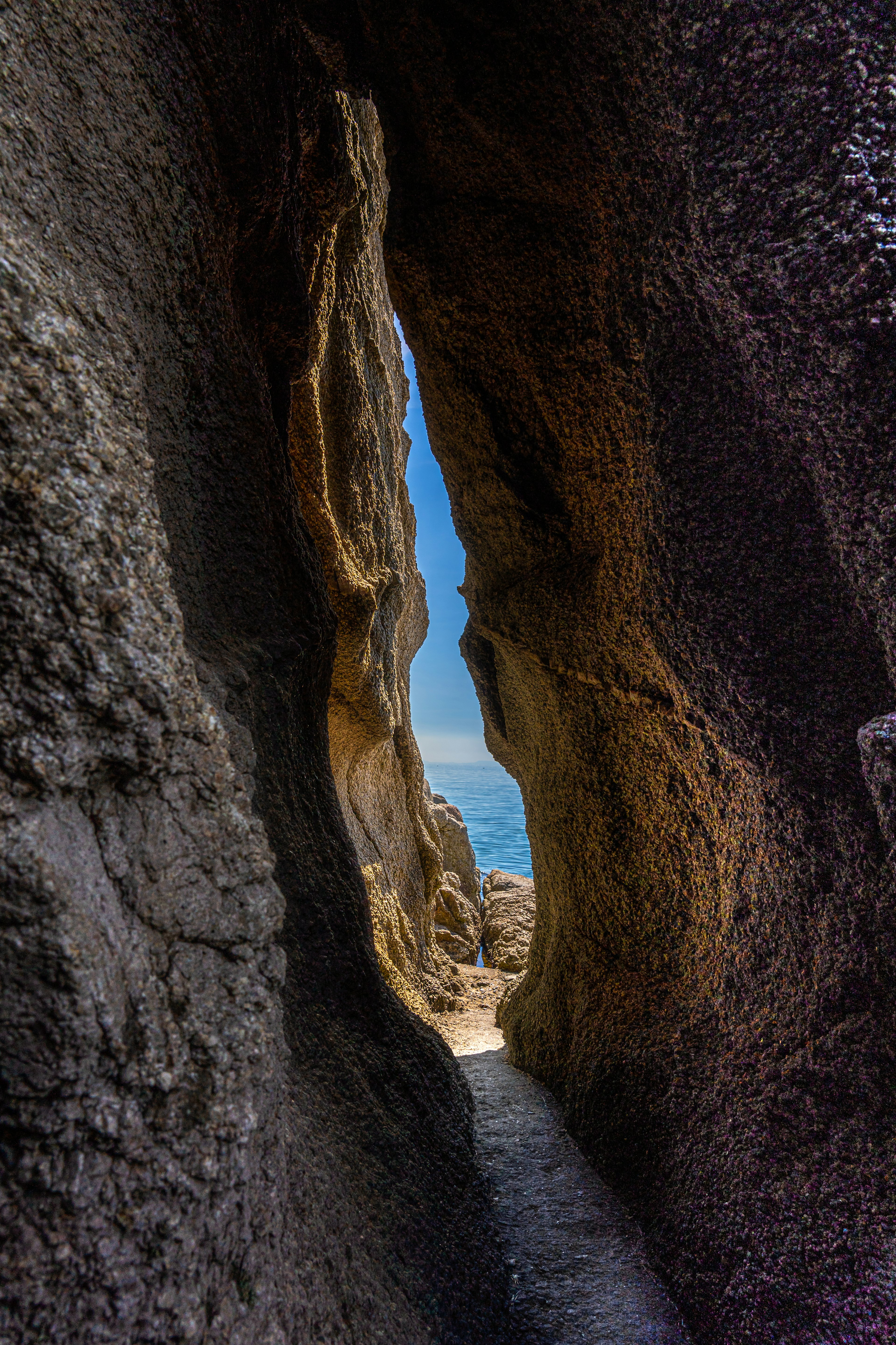 Vista tunnel tra le rocce che rivela il mare