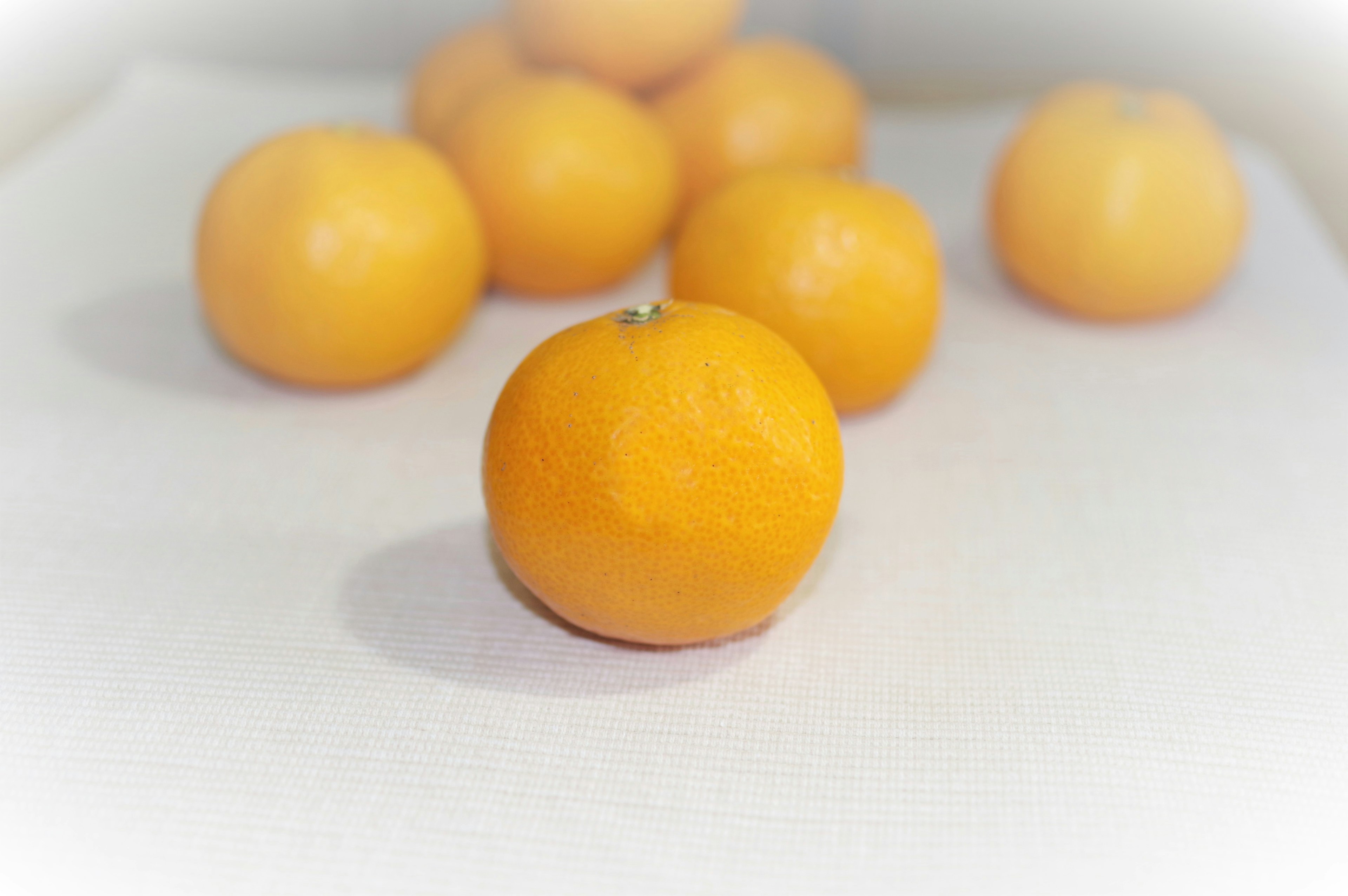 Une mandarine orange vibrante entourée de plusieurs autres sur une surface blanche