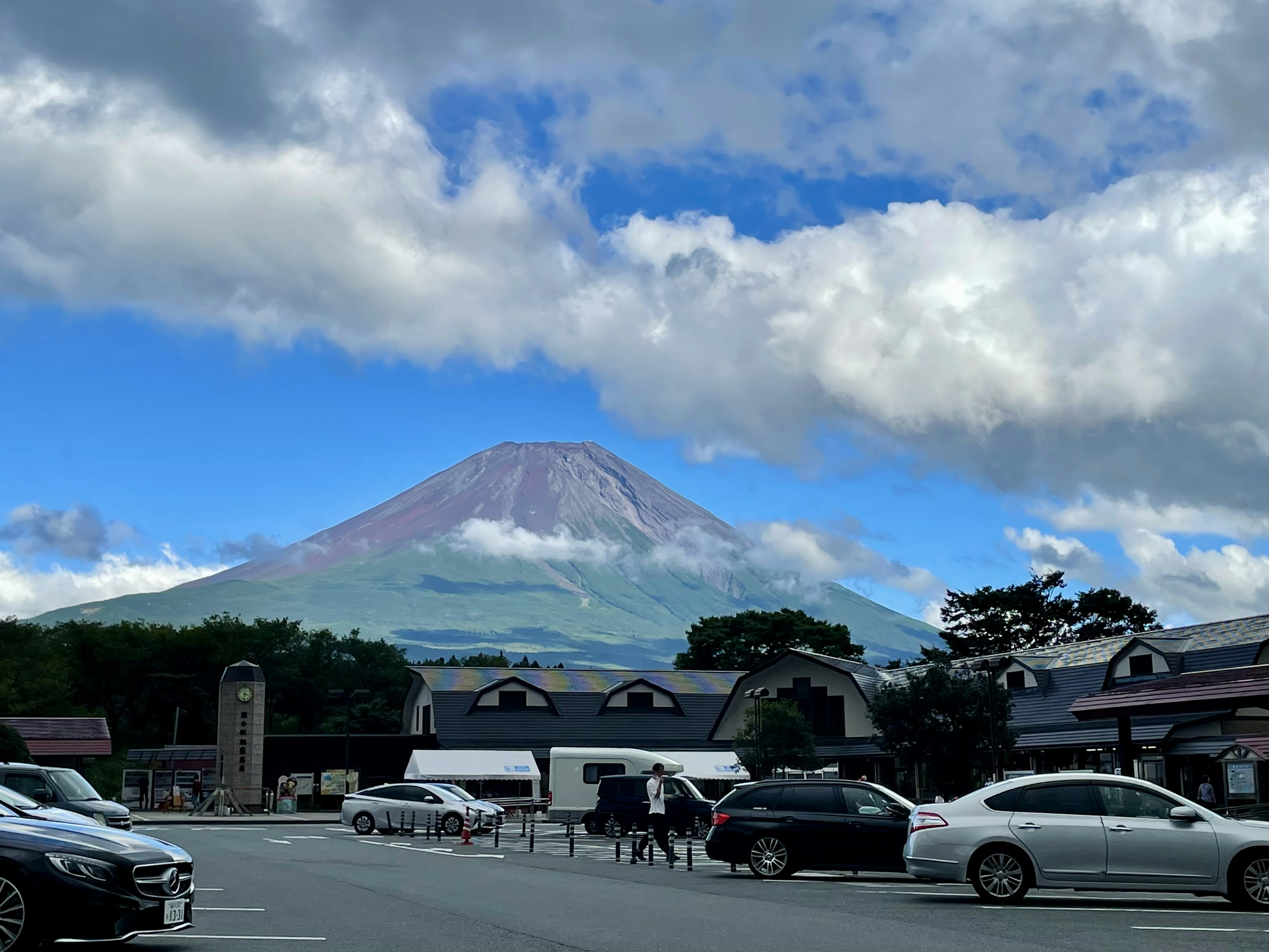 Mount Fuji with a blue sky in the background parking lot filled with cars