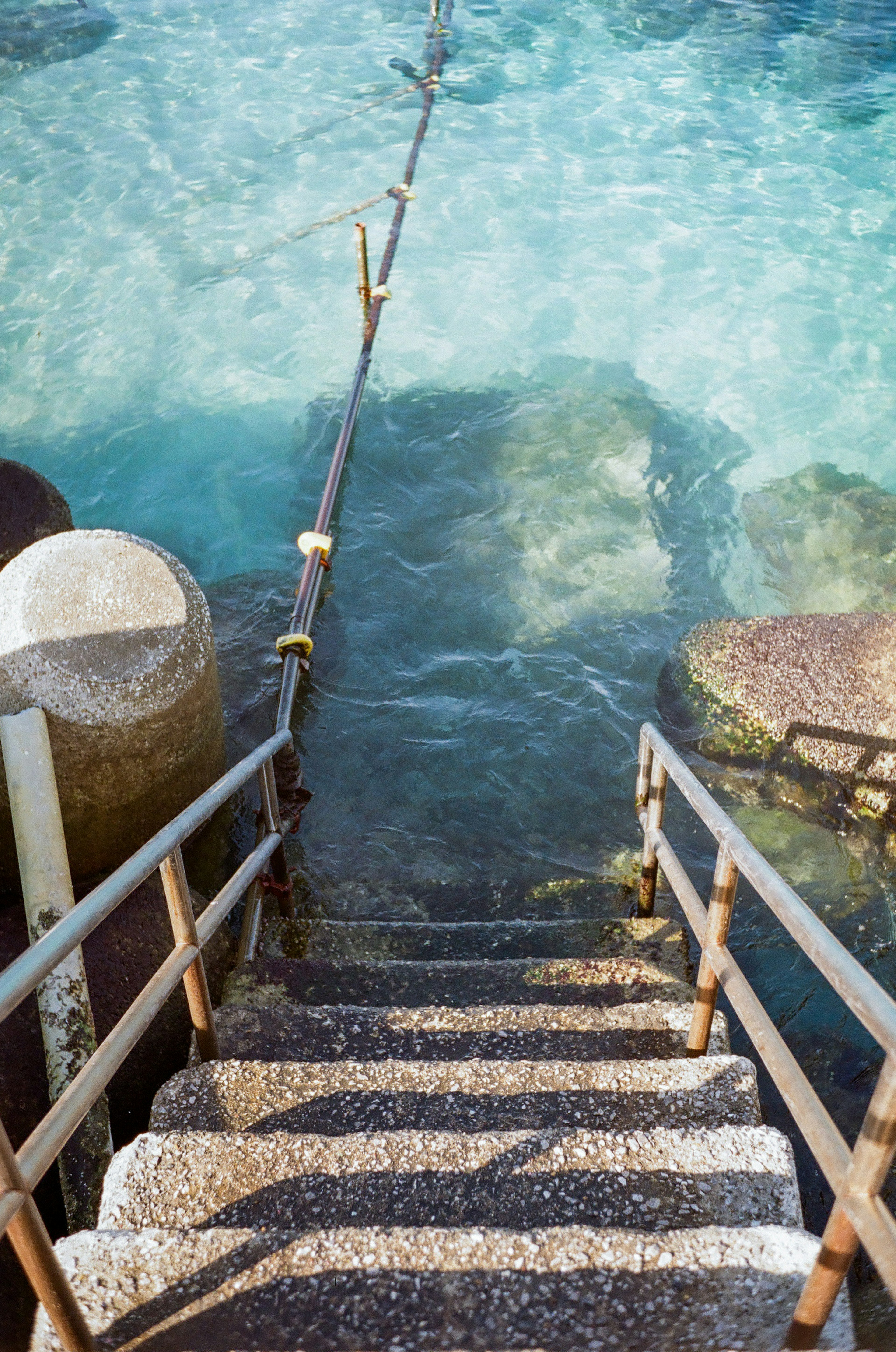 穏やかな青い海の水面に向かう石の階段と木の手すり