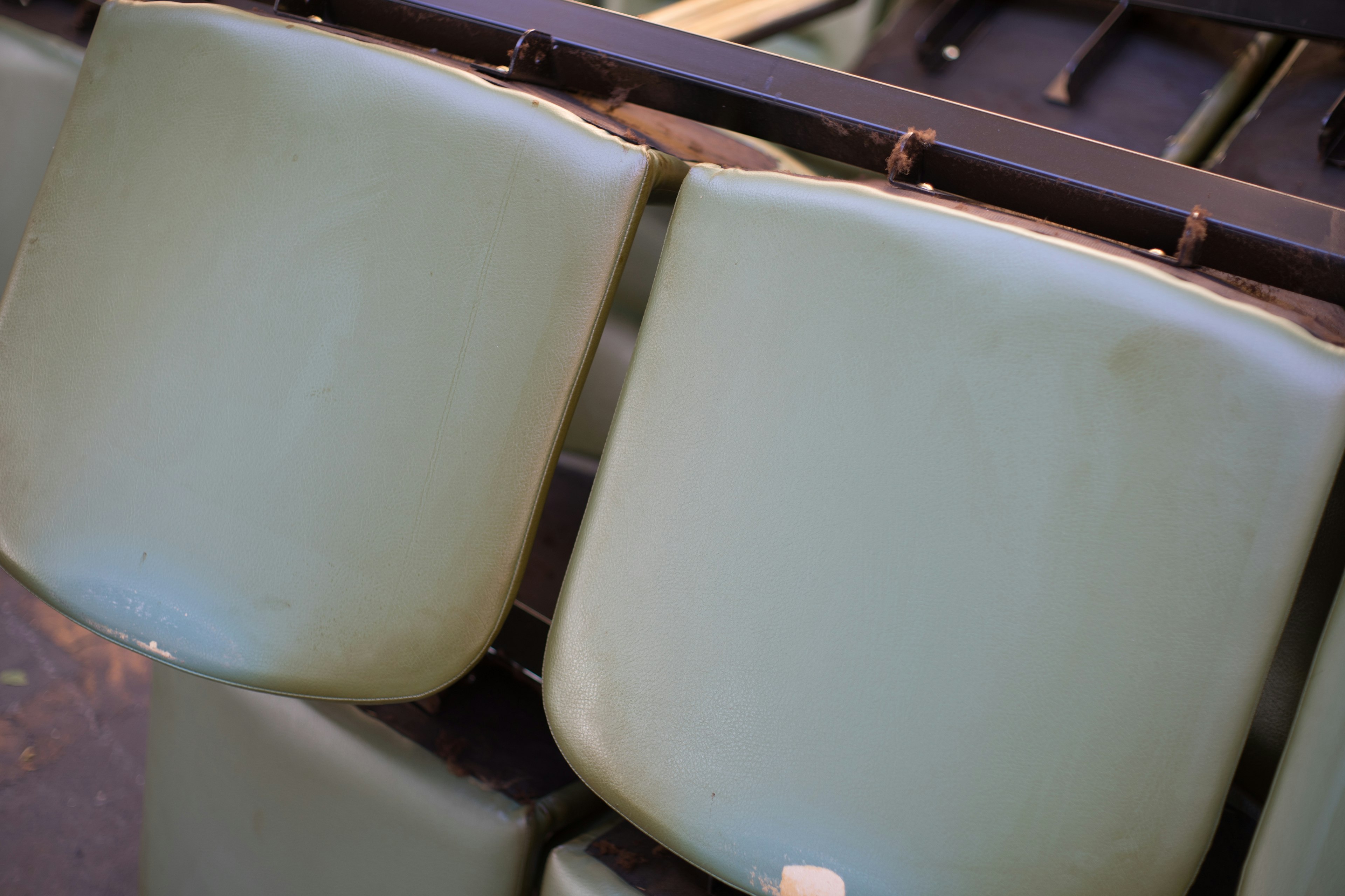 Close-up of pale green chair backs arranged in a row