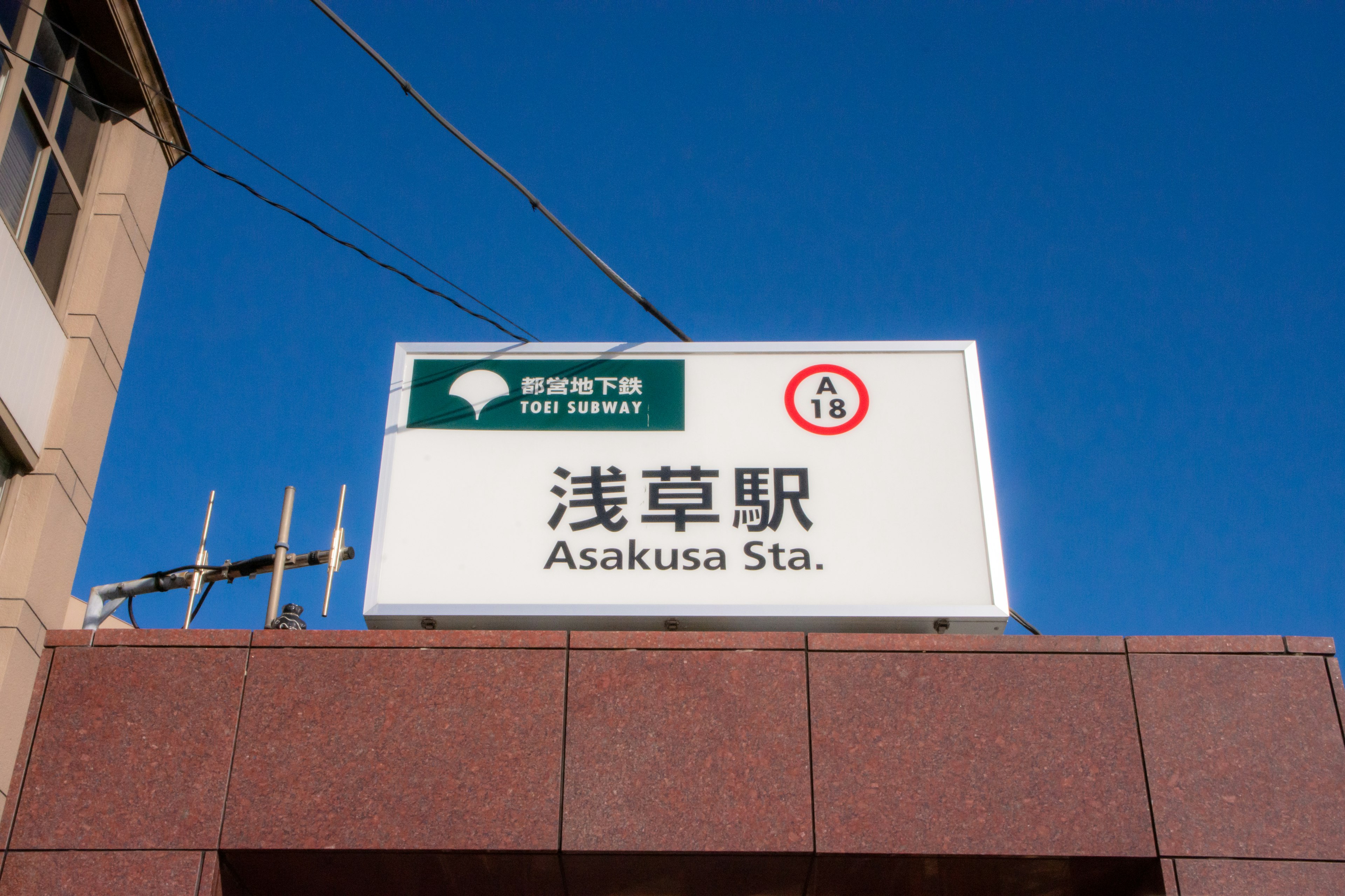 Schild für die Asakusa-Station unter einem klaren blauen Himmel