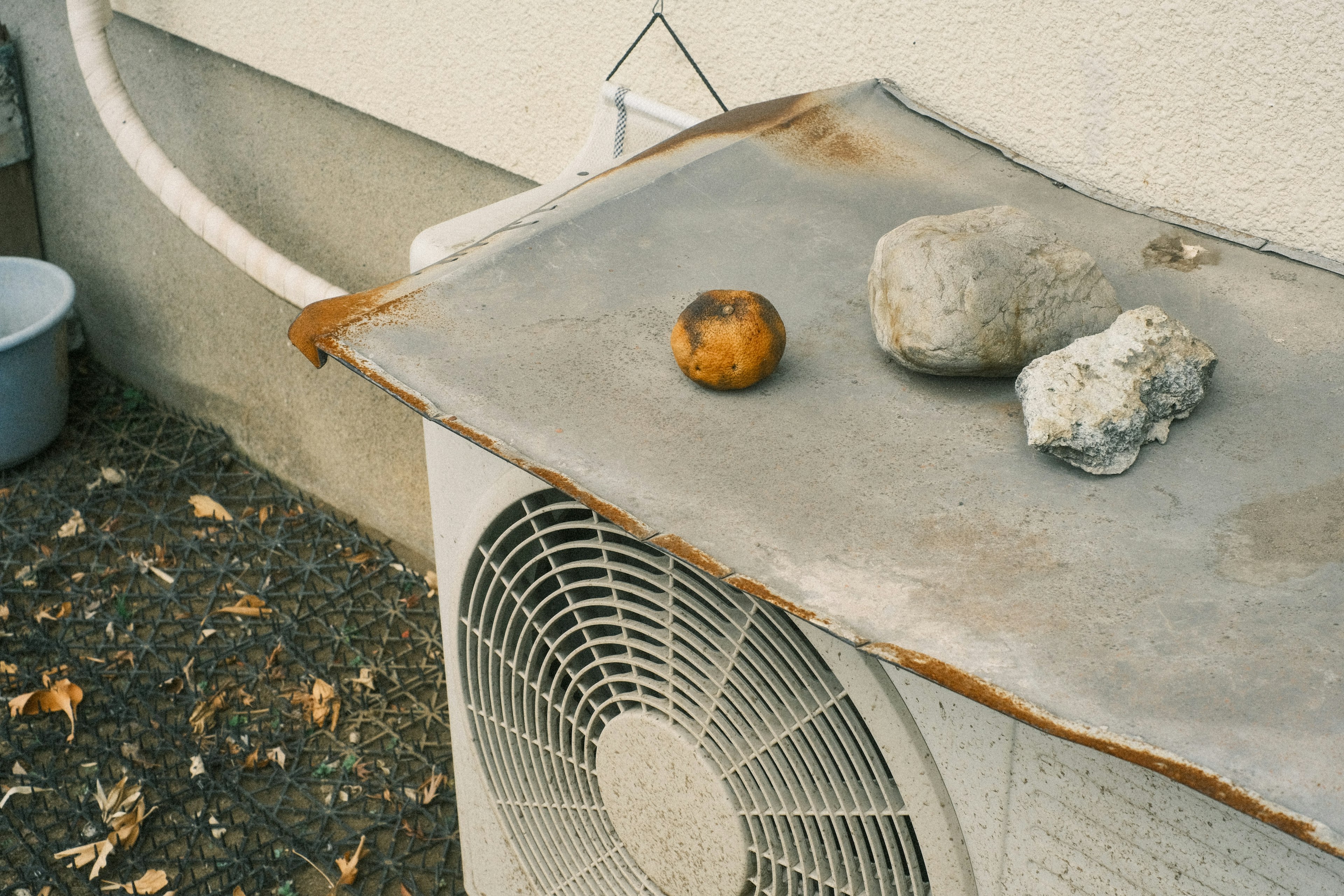 Steine und ein orangefarbenes Objekt auf einer Klimaanlage