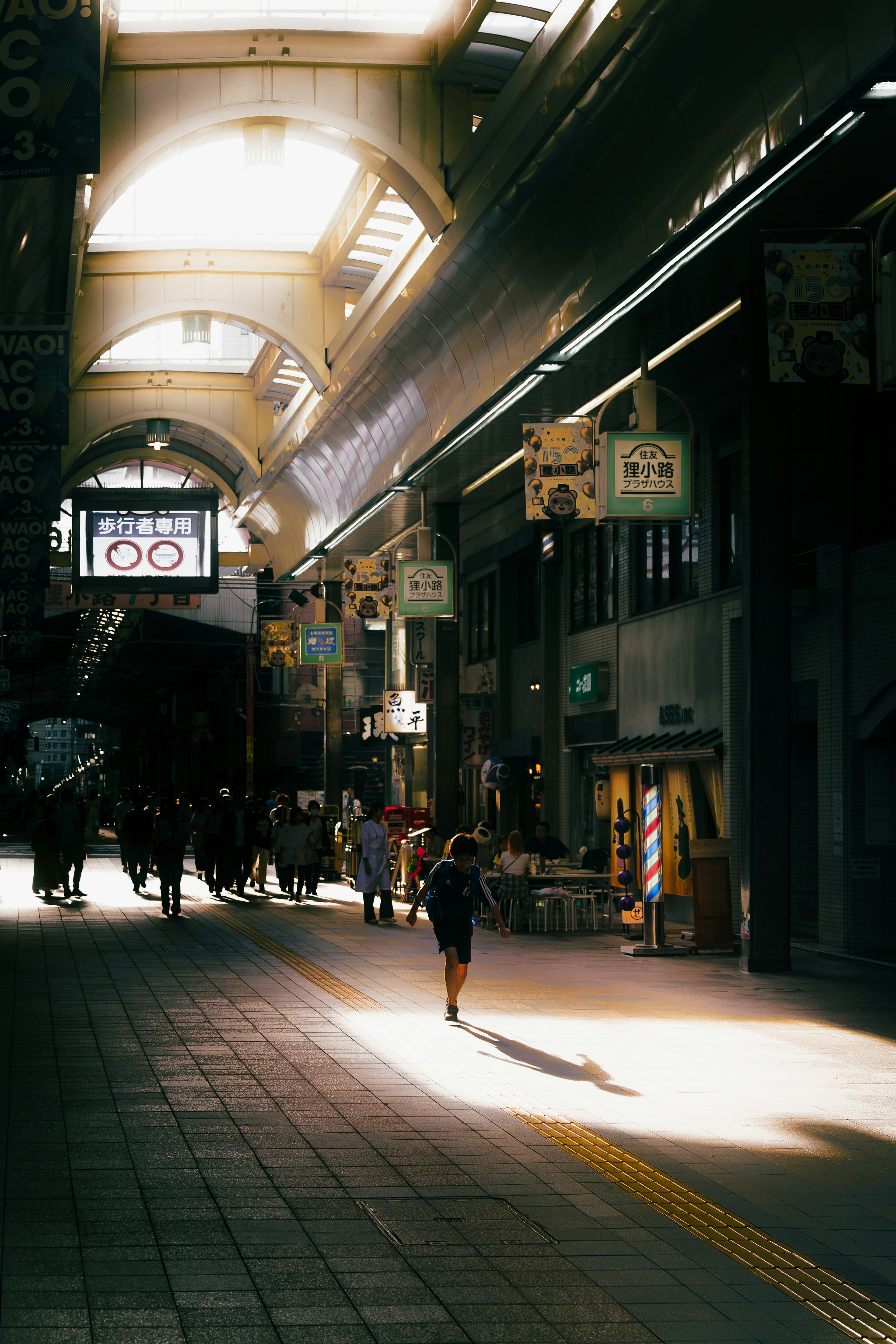 Una calle comercial animada con luz solar que entra personas caminando