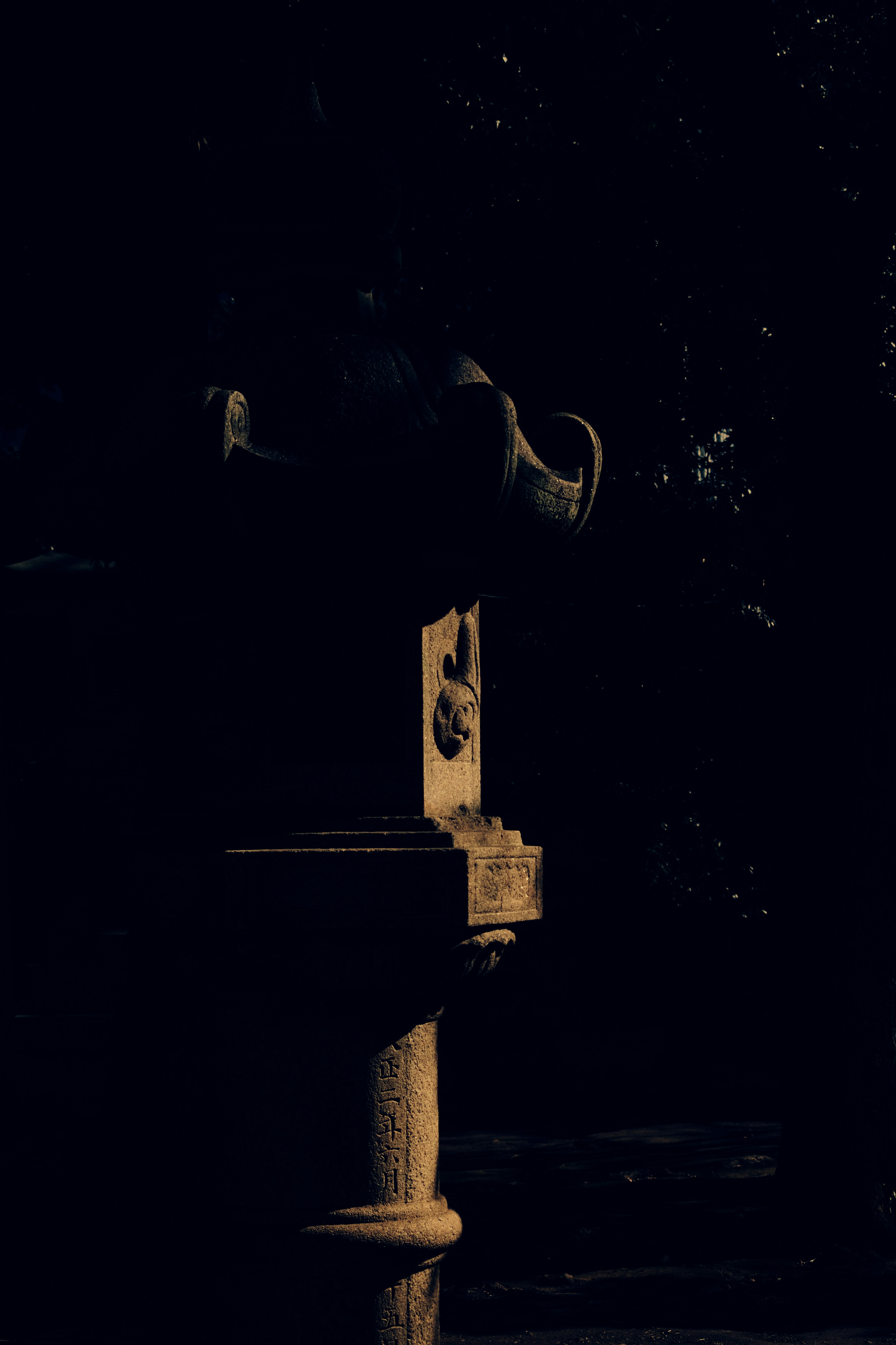 Part of a sculptural drinking fountain illuminated against a dark background