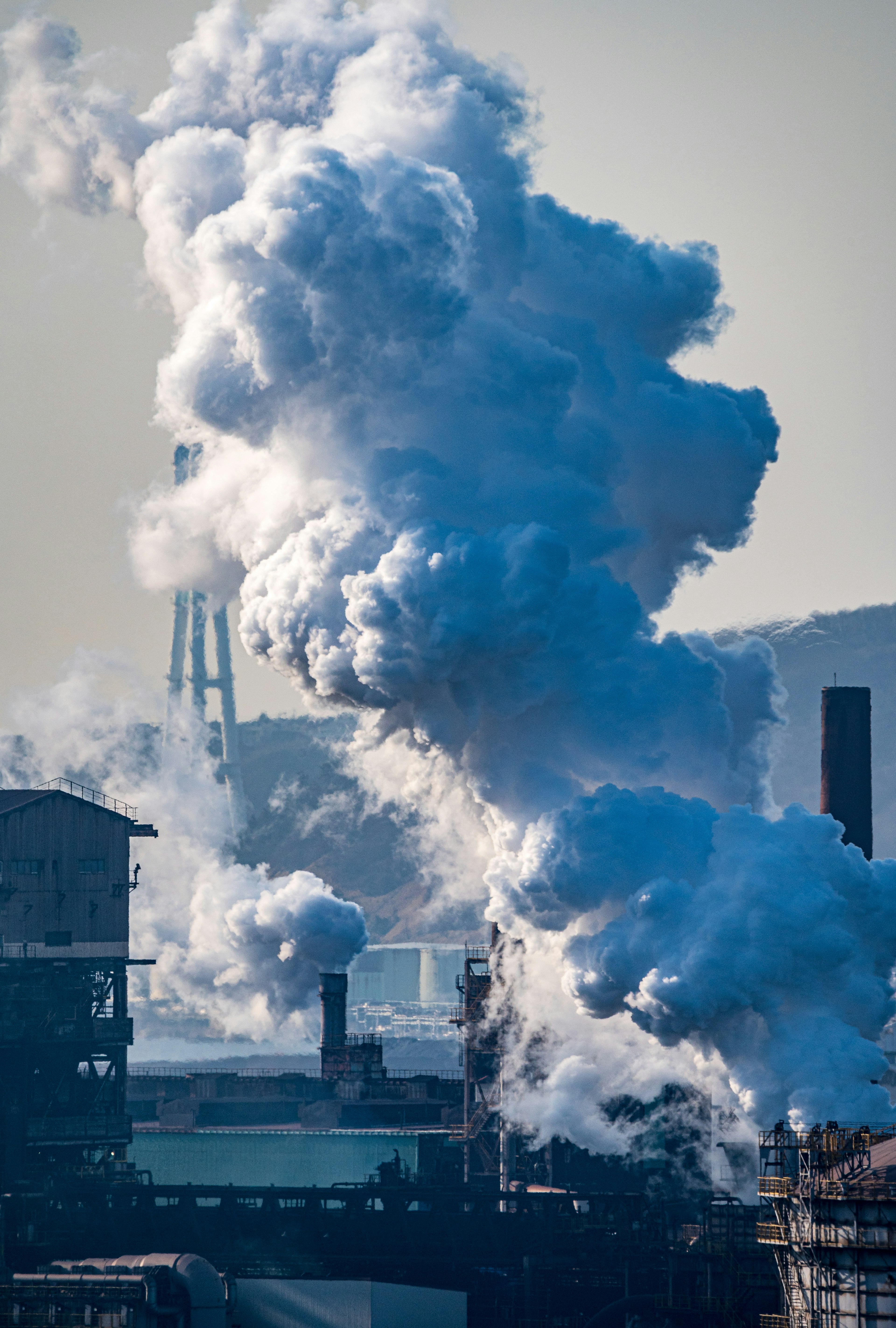 Humo saliendo de chimeneas industriales con siluetas de fábricas