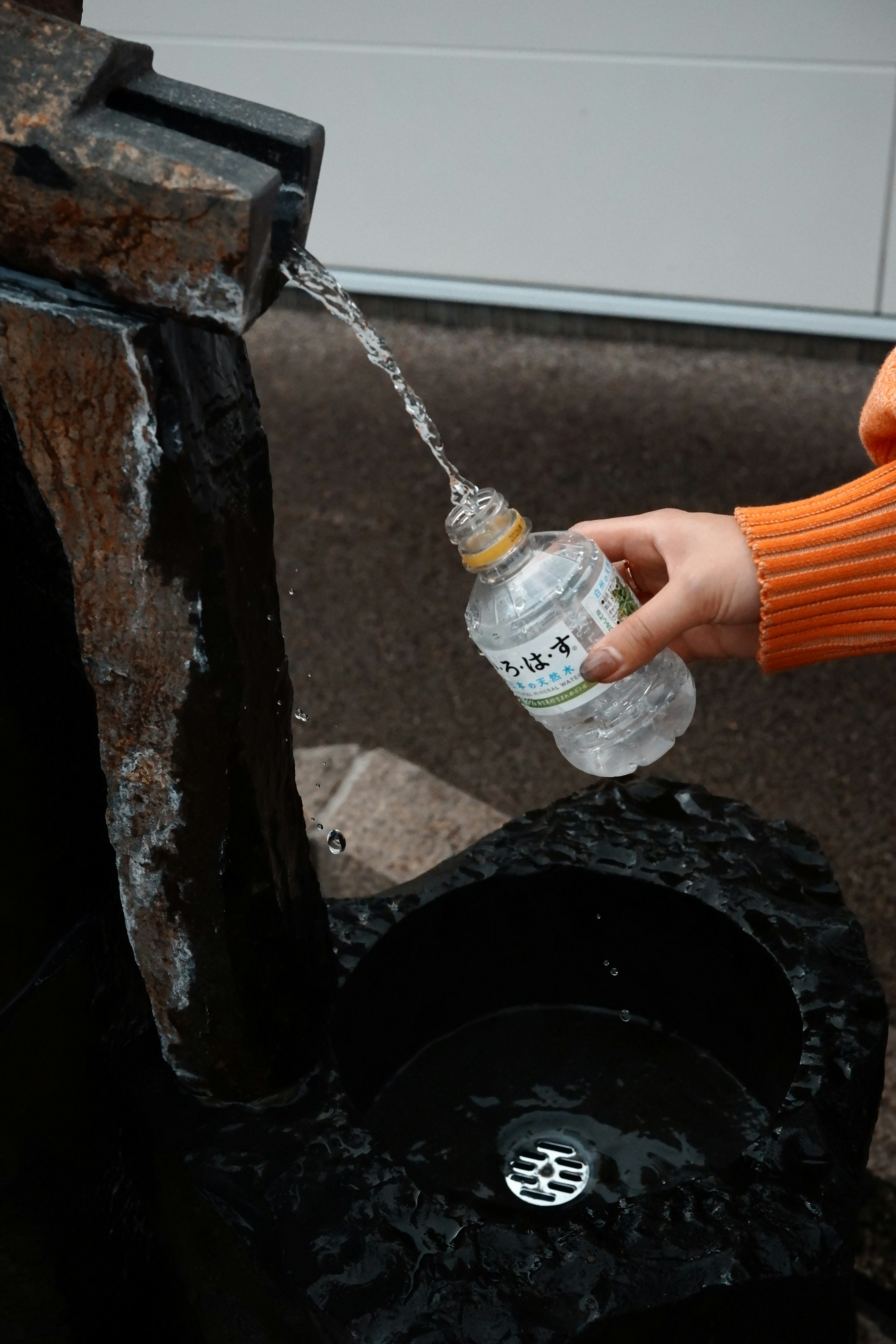 Bild einer Hand, die eine Flasche mit fließendem Wasser füllt