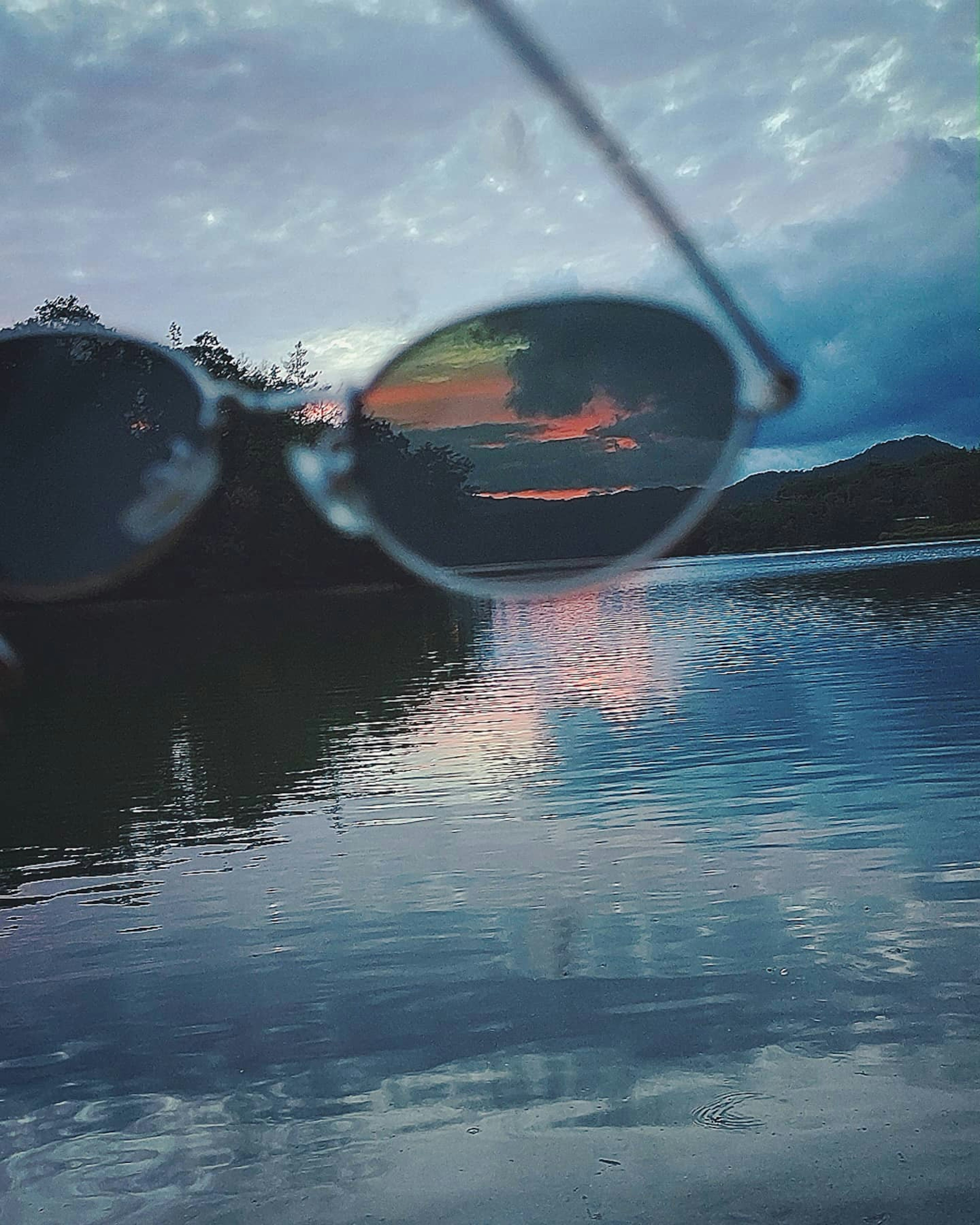 Reflejo del atardecer en el agua visto a través de gafas de sol