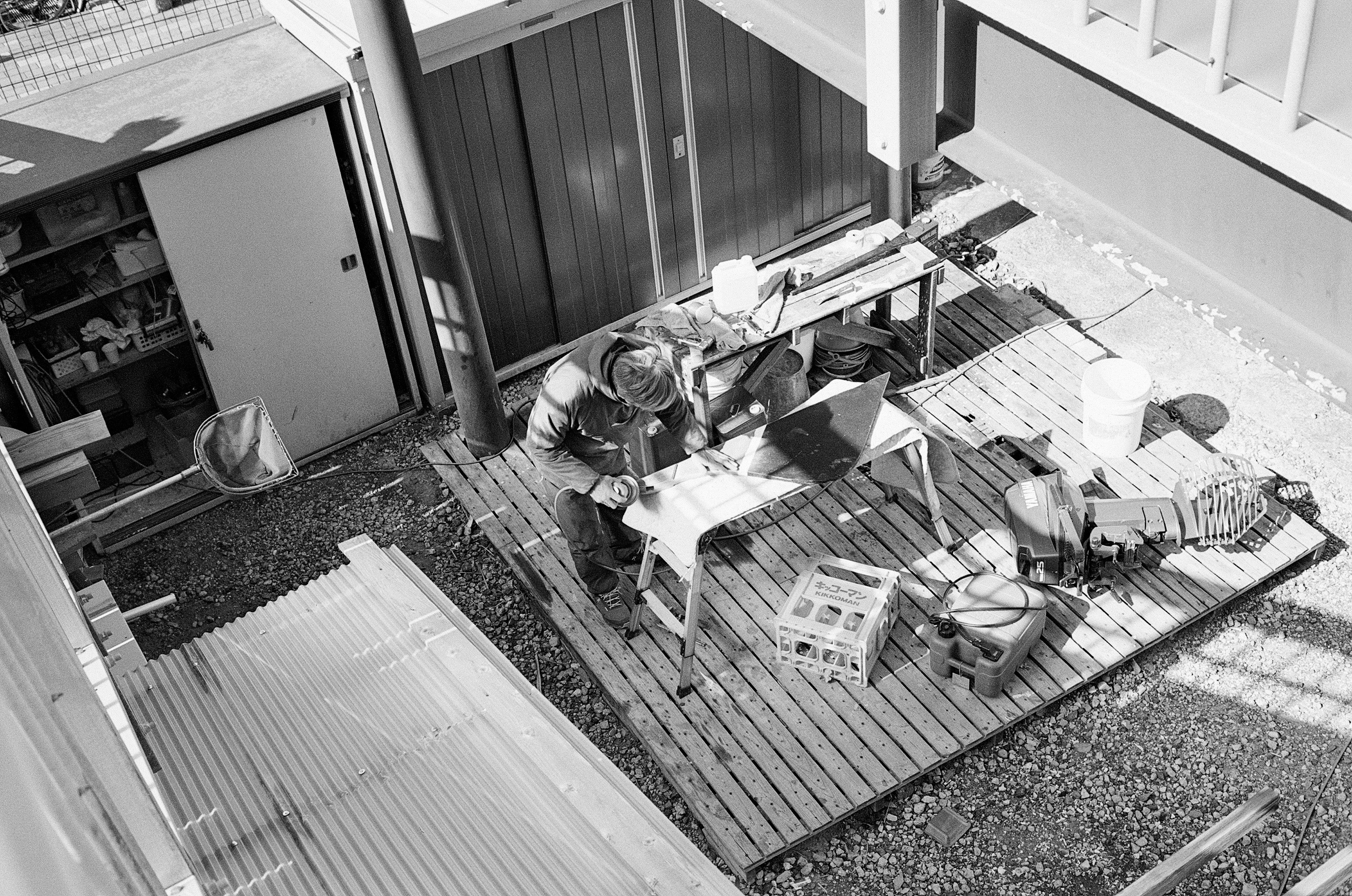 Black and white outdoor workspace with a person working and tools visible