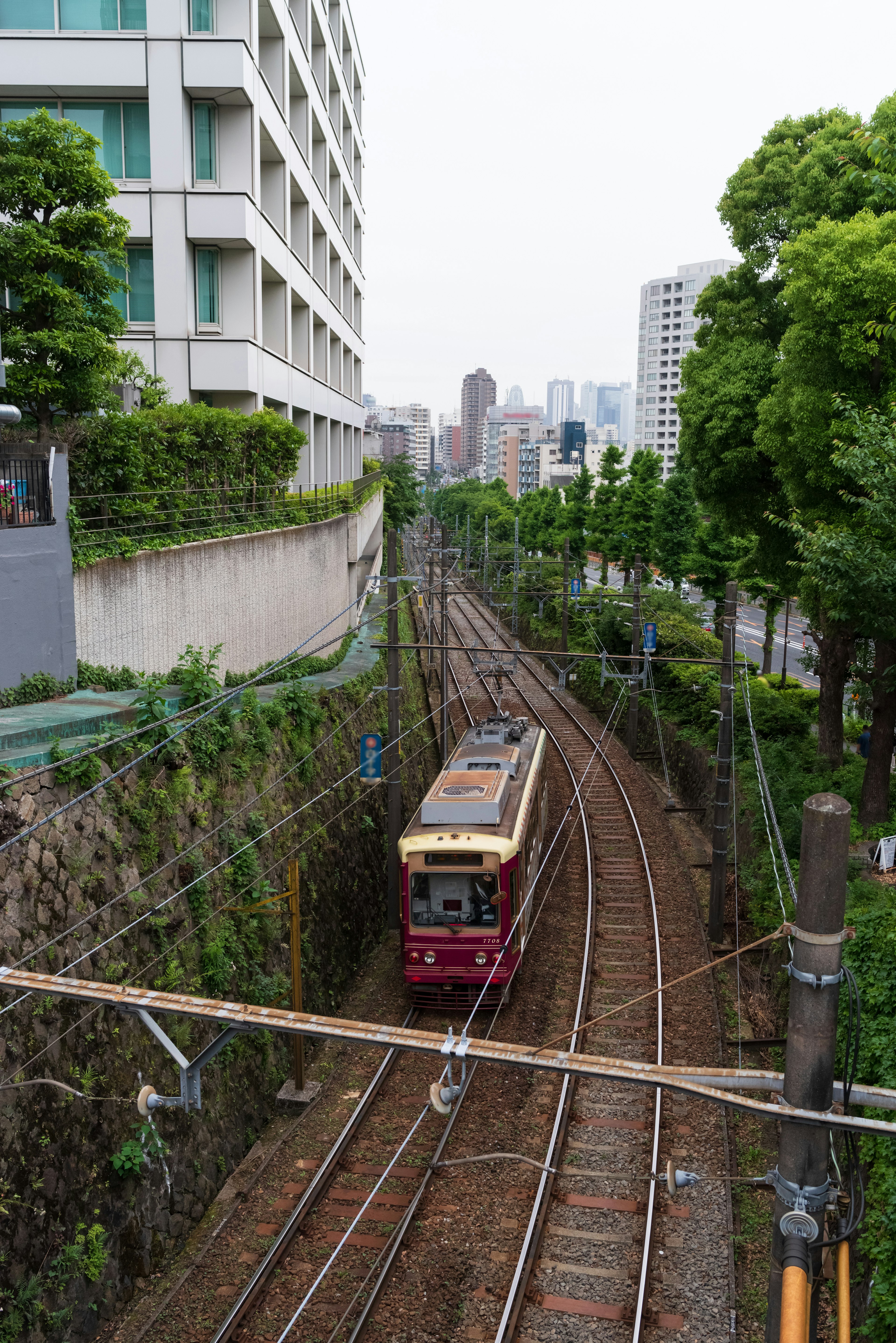 Red train passing through a green tunnel surrounded by buildings