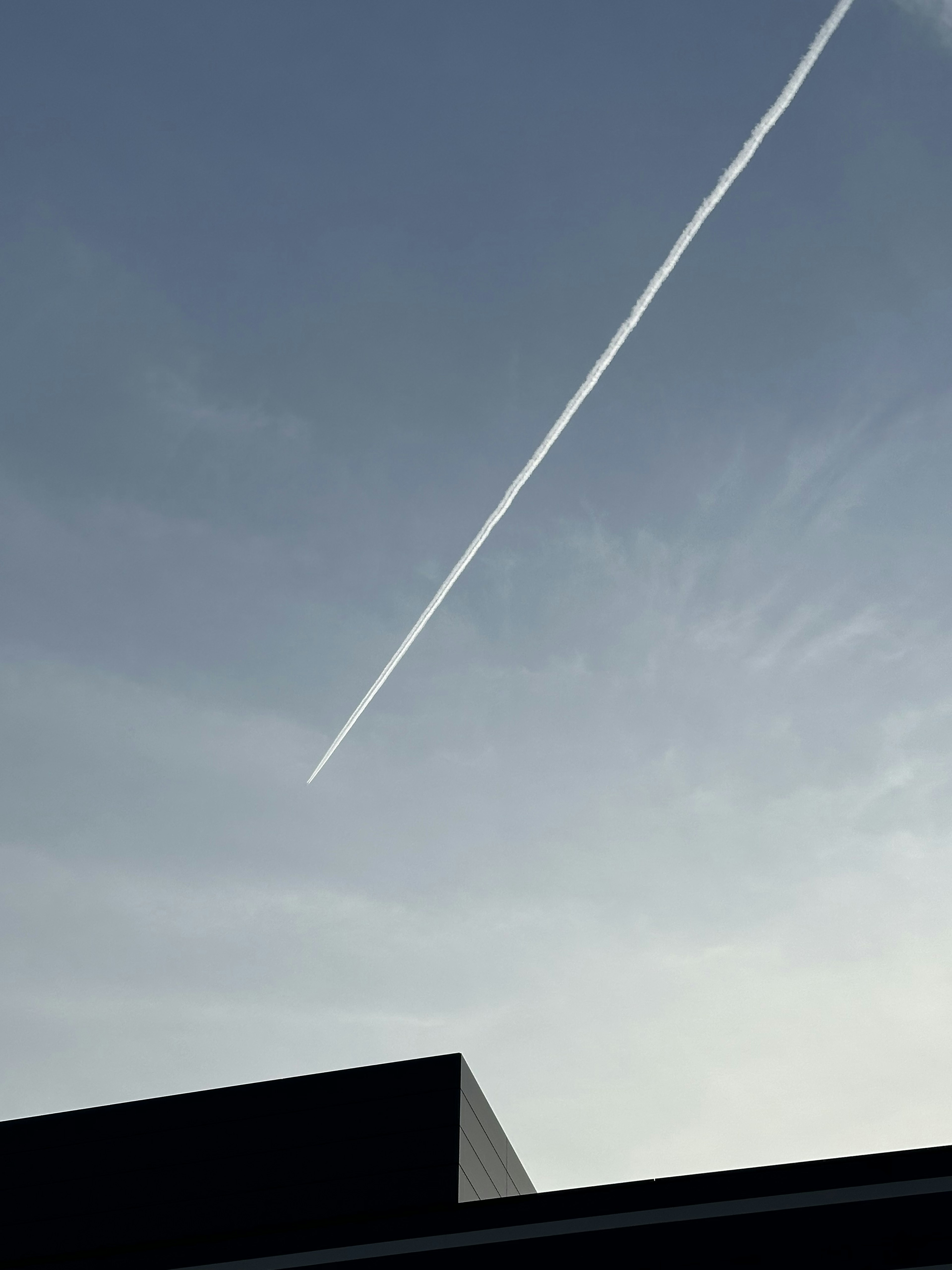 A contrail streaks across a clear blue sky