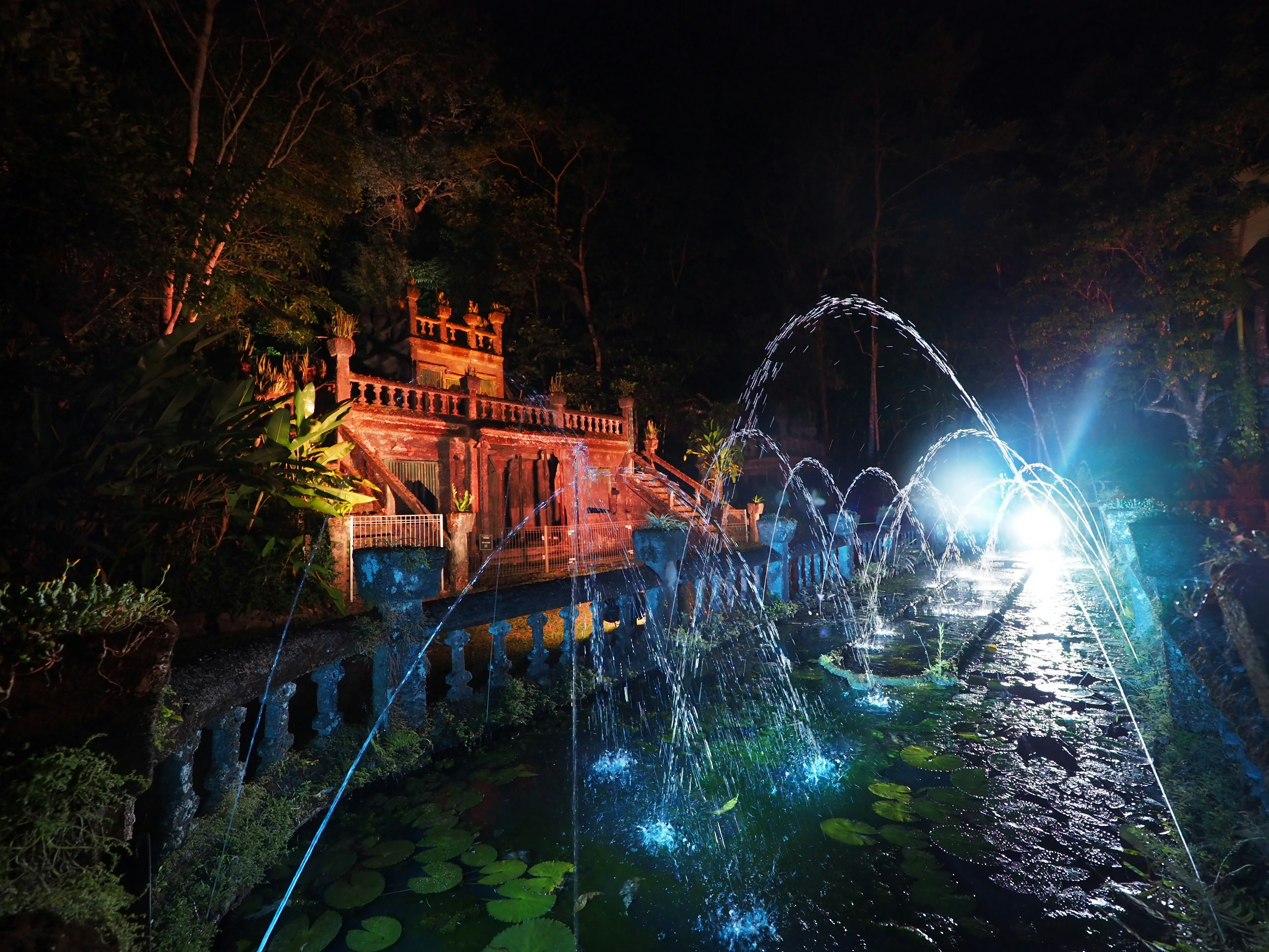 Schöne Szene mit Brunnen und Teich bei Nacht beleuchtet