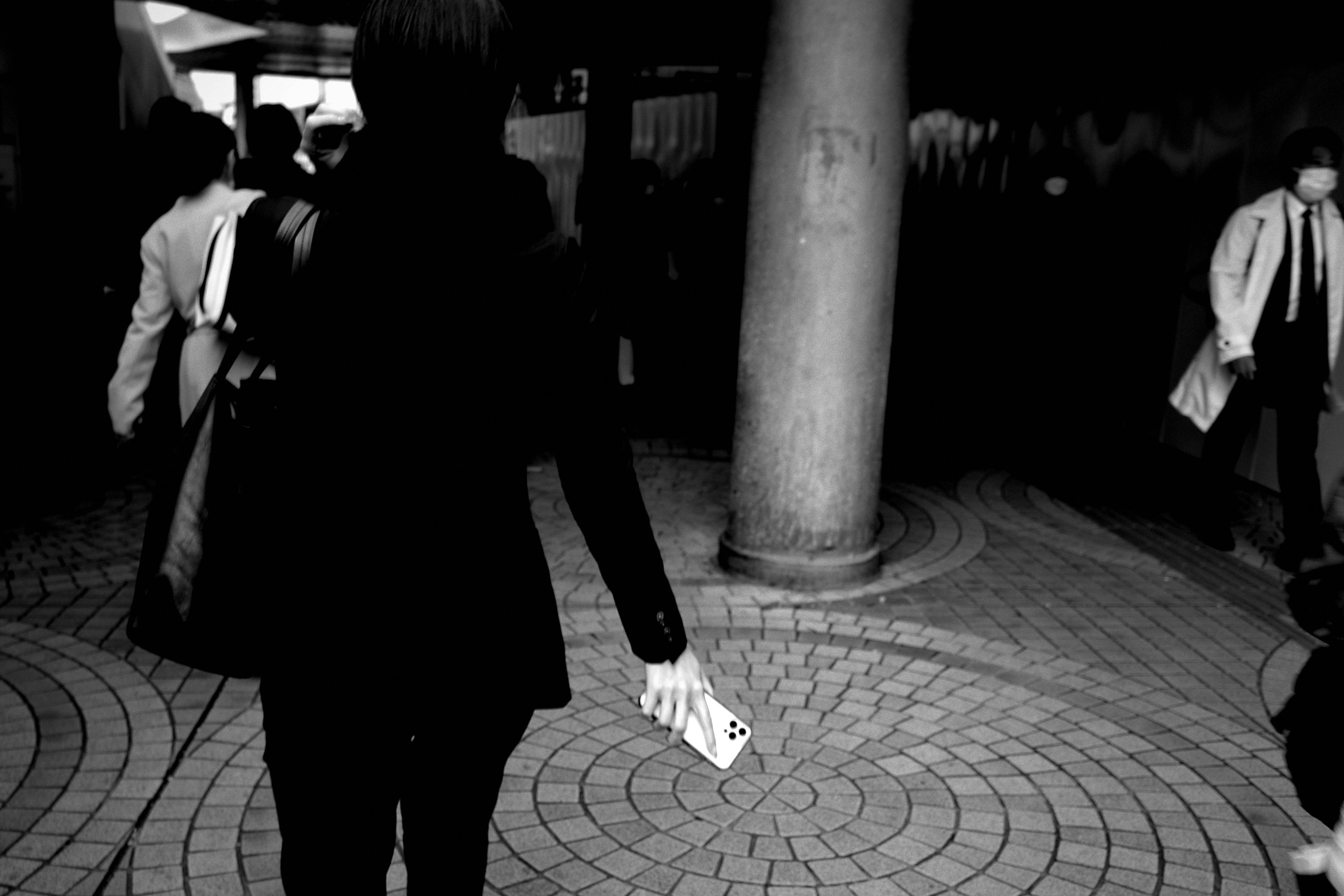 Black and white street scene with a person walking holding a piece of paper