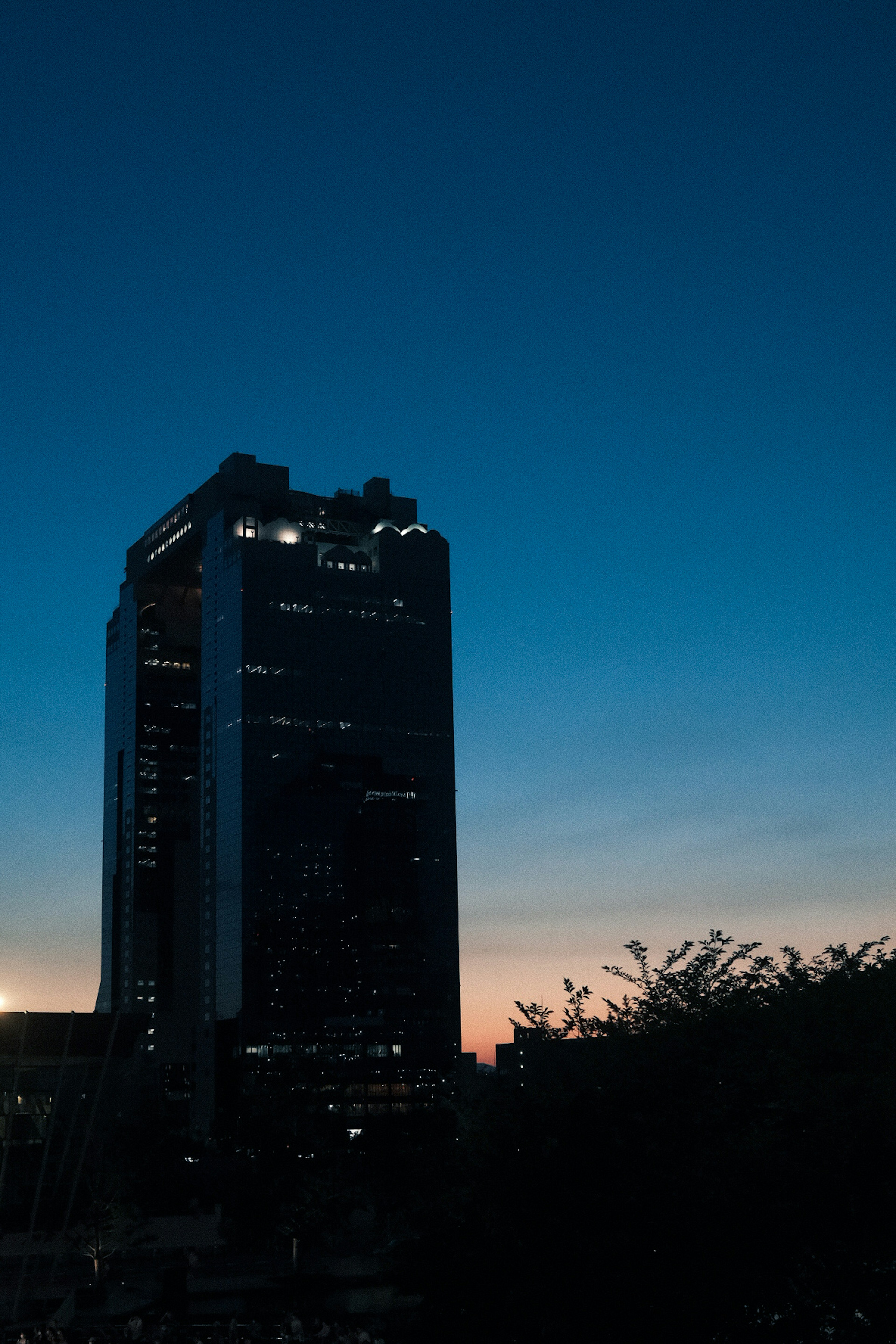 Silhouette d'un gratte-ciel contre un ciel crépusculaire avec des teintes de coucher de soleil