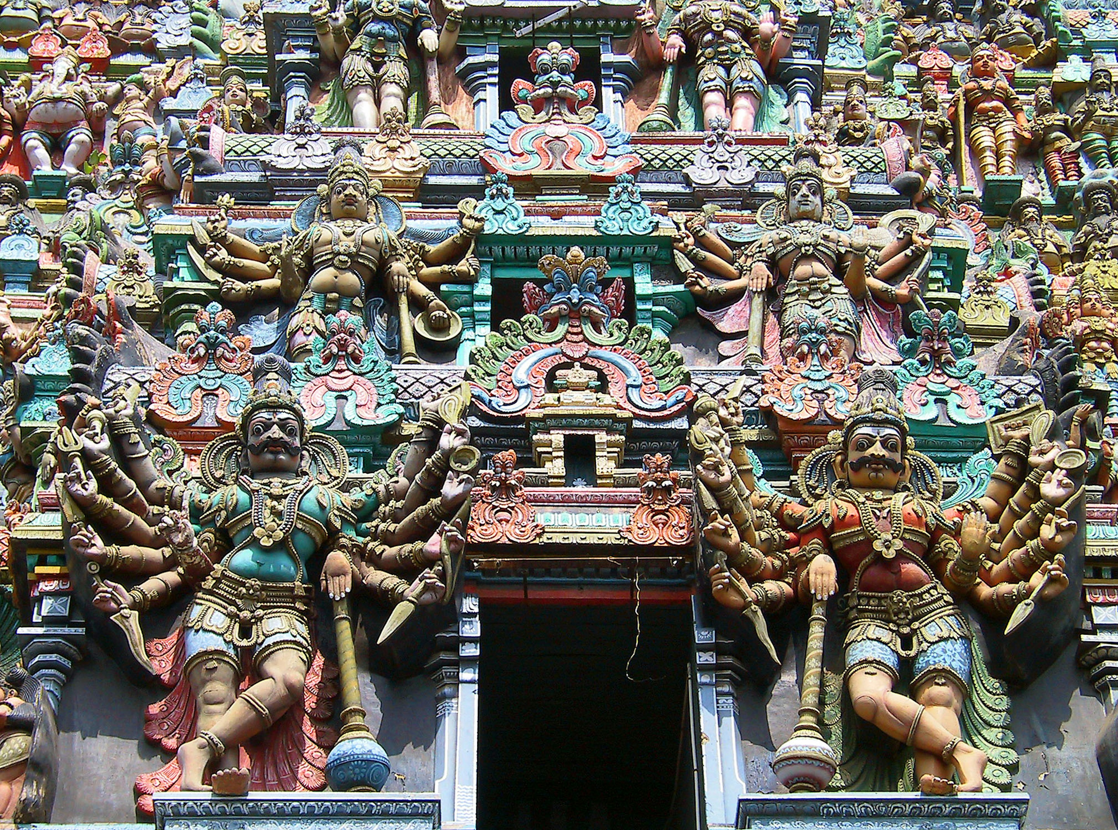 Vibrant temple facade featuring intricate sculptures of deities and warriors