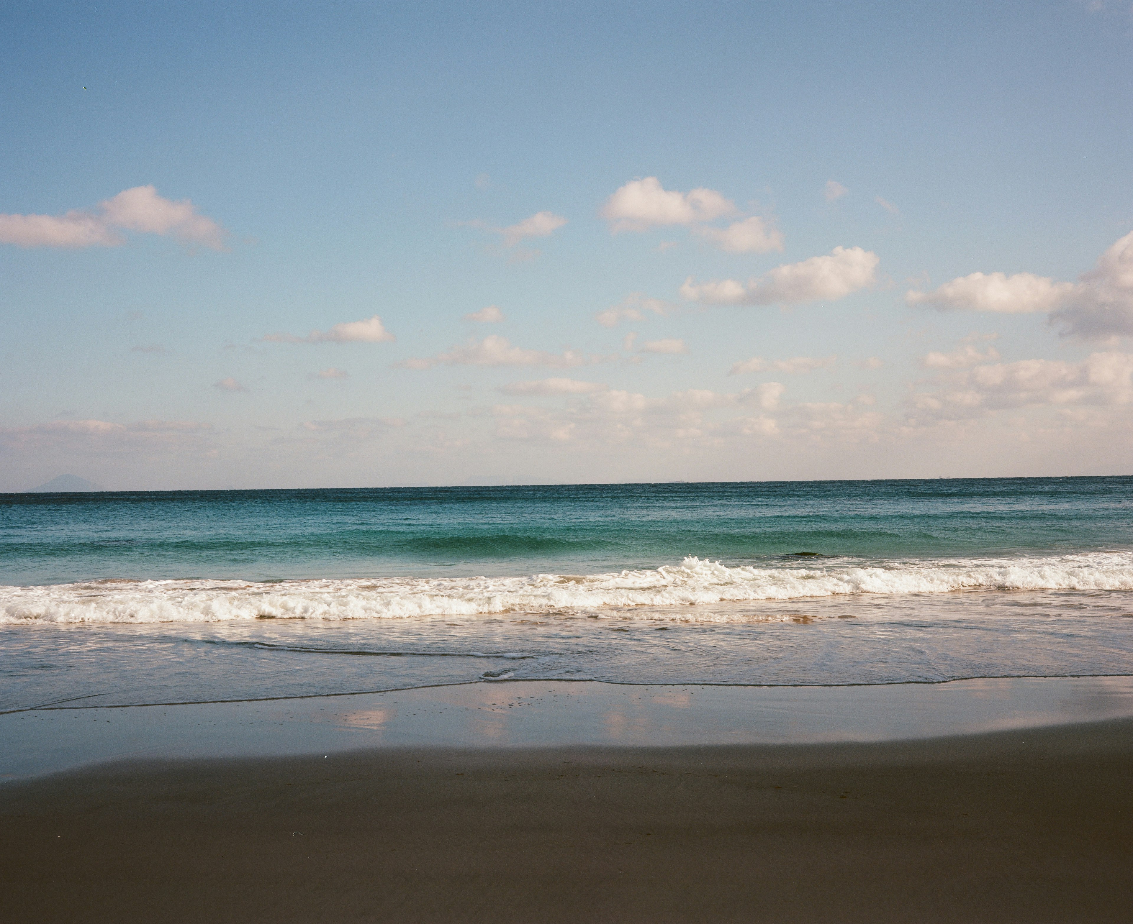 Malersicher Blick auf einen Strand mit blauem Wasser und weißen Wellen