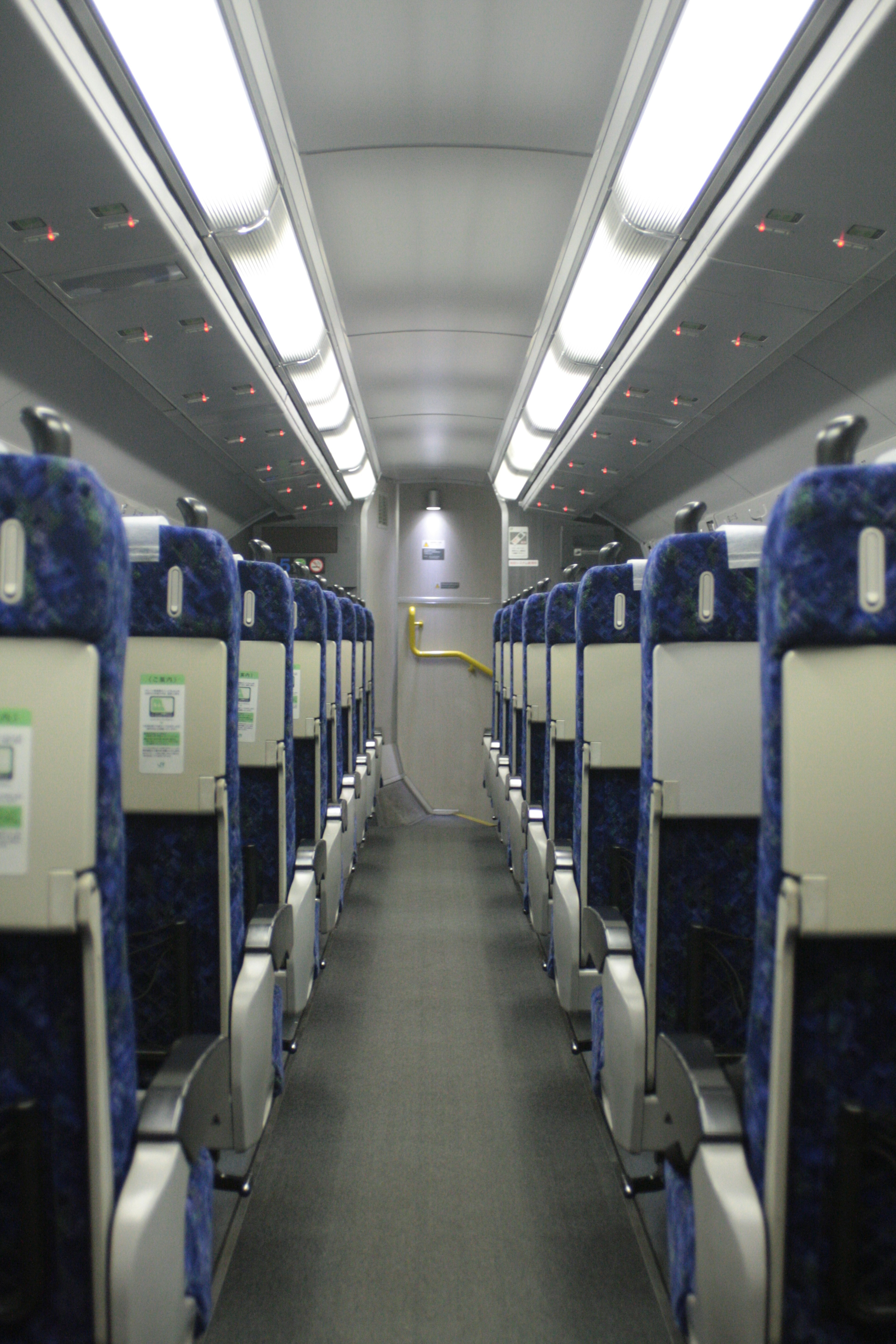 Interior de un vagón de tren vacío con asientos acolchados azules