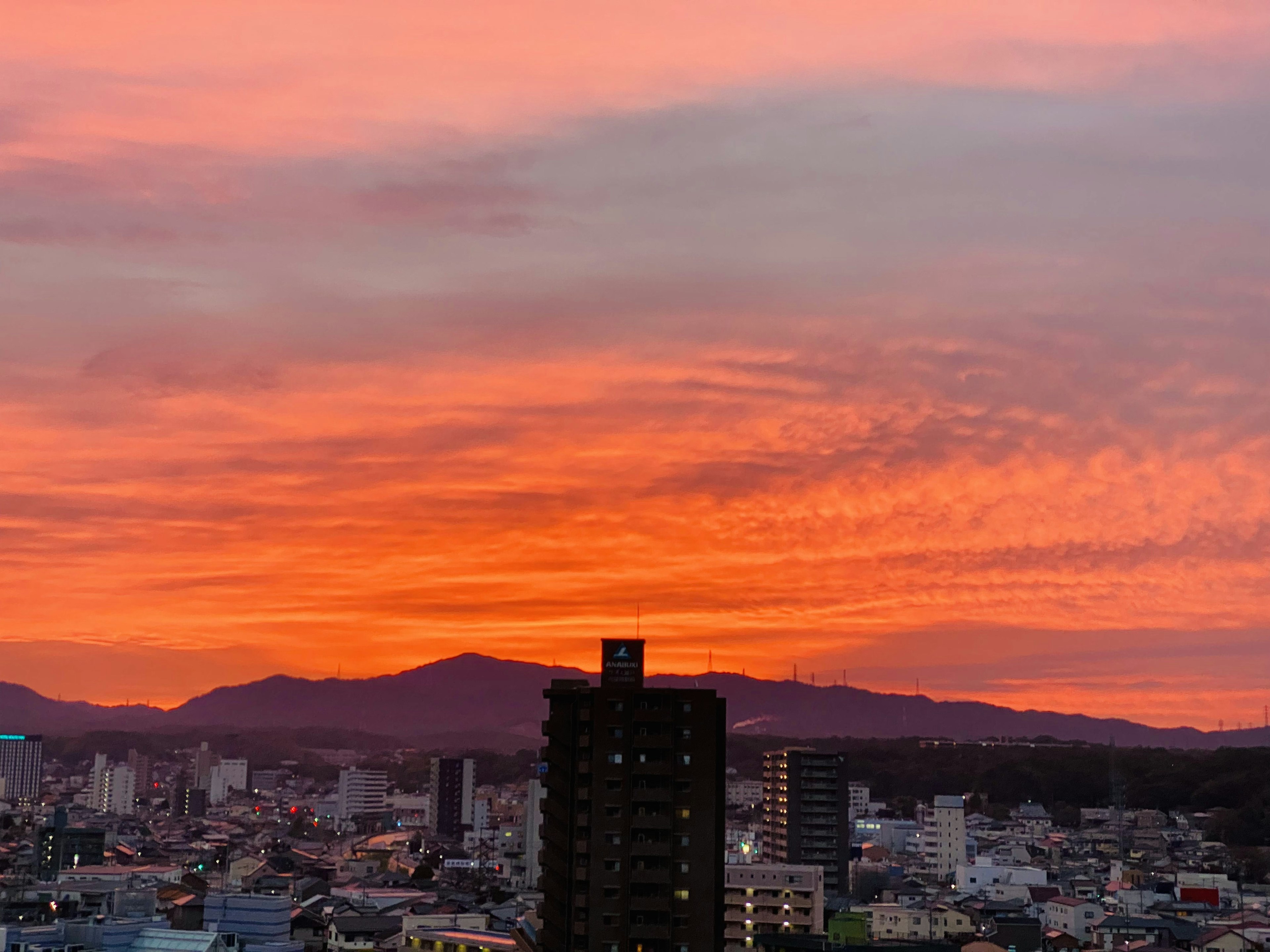 Wunderschöner Sonnenuntergang über einer Stadtlandschaft mit Hochhäusern und Bergen im Hintergrund