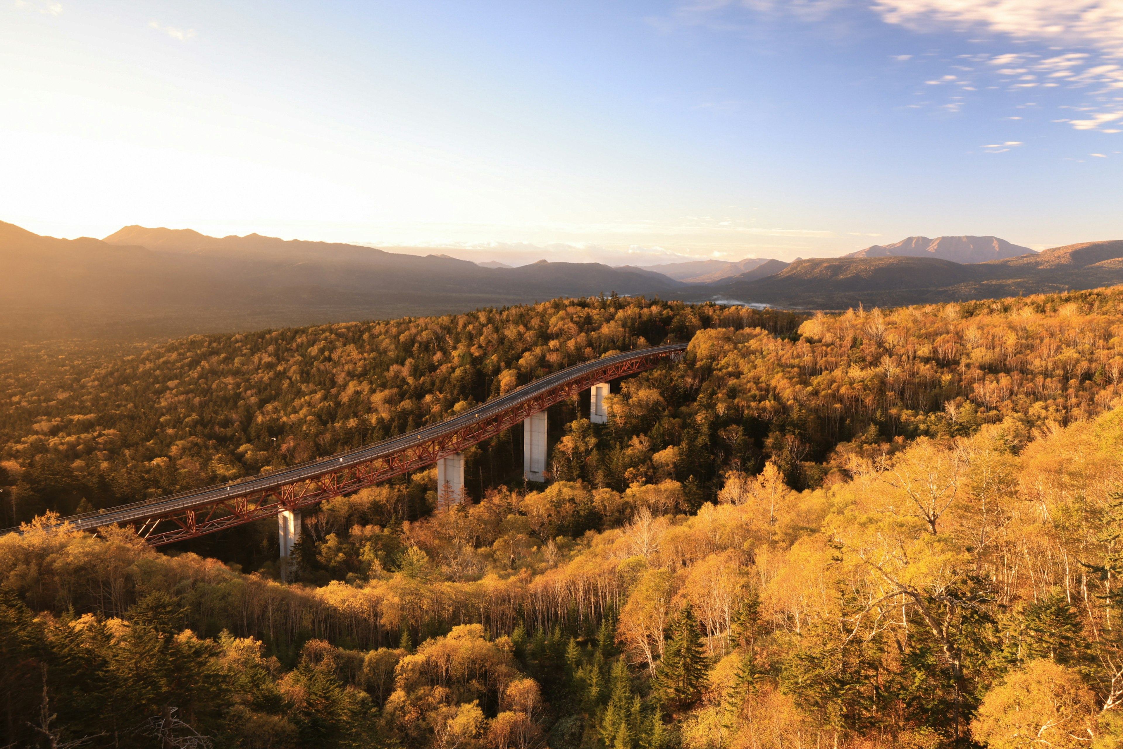 Una vista escénica de un puente rodeado de follaje de otoño y montañas