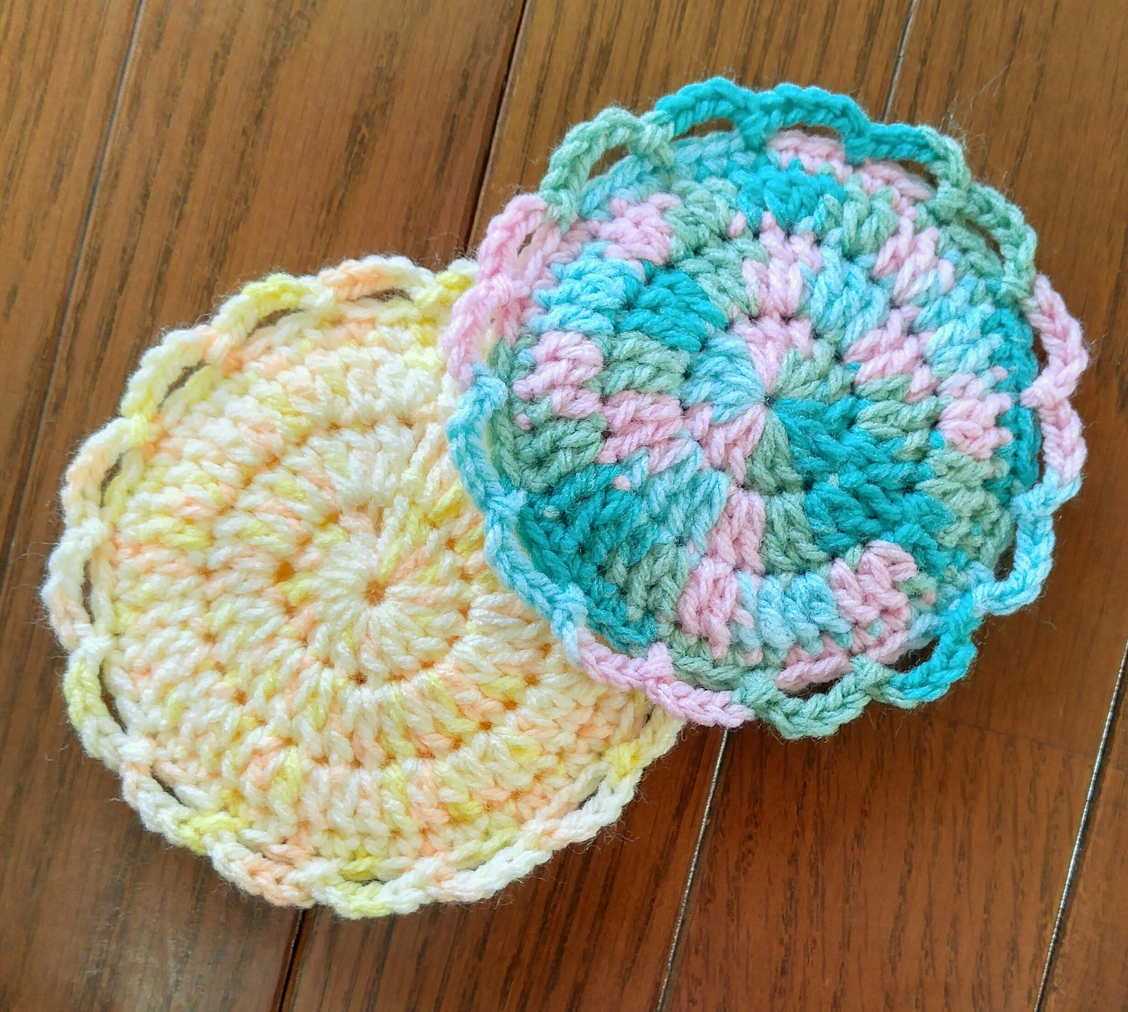 Two colorful crochet coasters placed on a wooden table